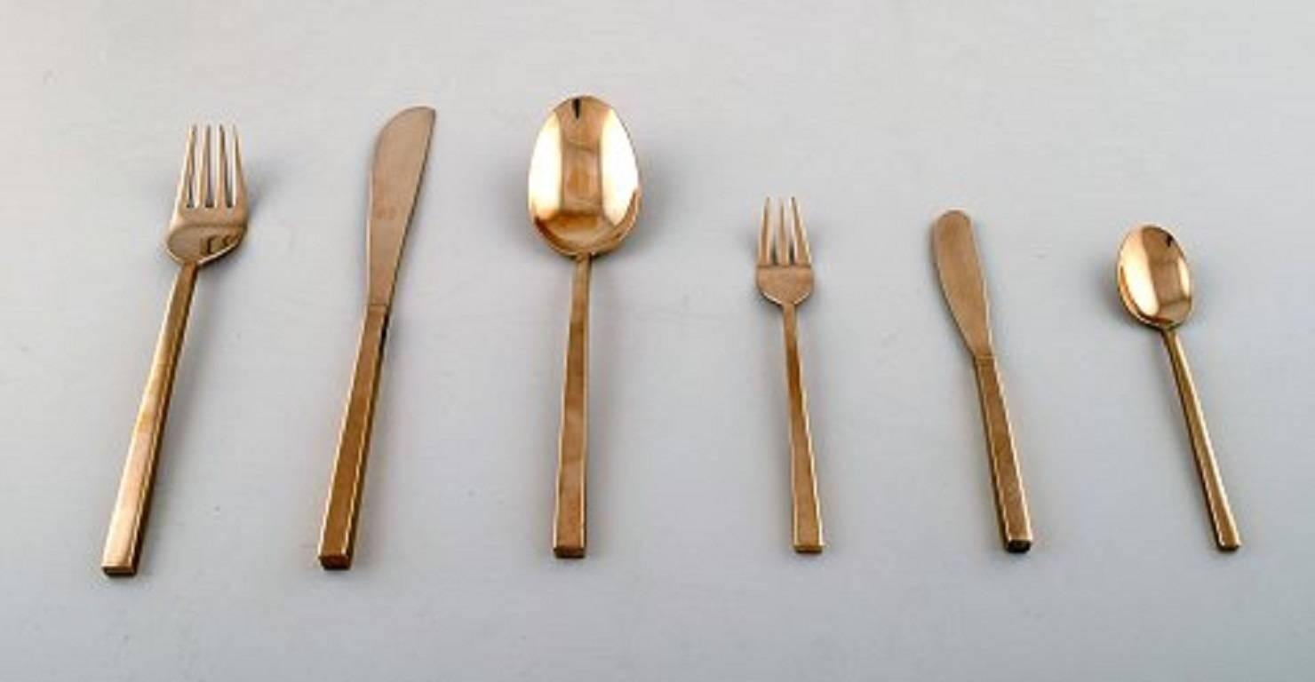 Sigvard Bernadotte 'Scanline' cutlery of brass complete for 12 place settings. Comprising: 12 dinner knives, 12 dinner forks, 12 soup spoons, 12 cake forks, 12 coffee spoons, 12 cheese / fruit knives, 12 butter knives, various serving items. 
A