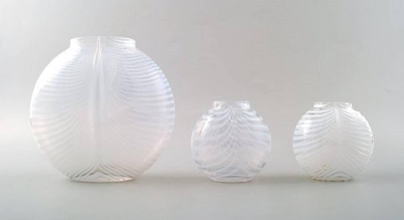 Large collection of nine Scandinavian handcrafted art glass vases from the Zebra series designed by Bertil Vallien for Kosta Boda.
The oval pillow shaped vase features opalescent milky white stripes pulled in a feather like pattern that masterfully