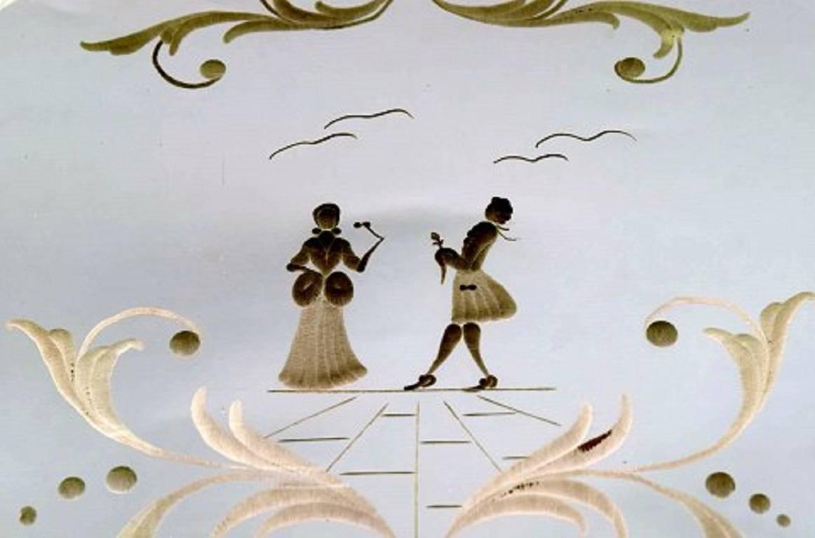 Murano, Italie, plateau rectangulaire avec plaque en miroir, motif floral avec scène galante, deux poignées en métal doré sur le côté.
Longueur approximative de 34 cm (avec la poignée), largeur approximative de 25 cm.
En parfait état.