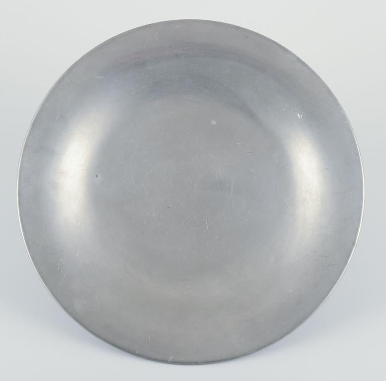 Los productos de segunda mano están exentos de derechos de importación para los clientes estadounidenses. 
Por lo tanto, no se aplicarán aranceles de importación a tu compra.

Just Andersen (1884-1943).
Plato Art Decó temprano en peltre.
Citas: Ca.