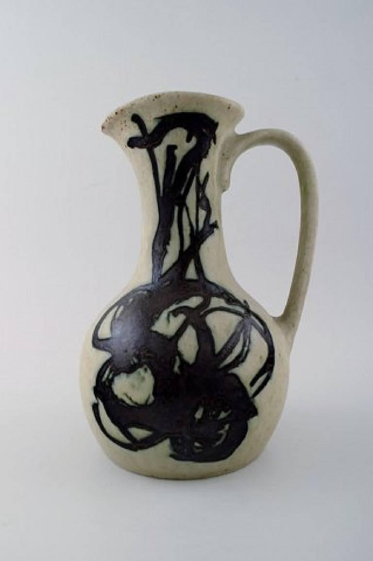 Mogens Andersen for Royal Copenhagen: 
Stoneware pitcher decorated with matt, grey glaze and black glazed patterns. 
H. 24.5 cm.
In perfect condition. 1st. factory quality.