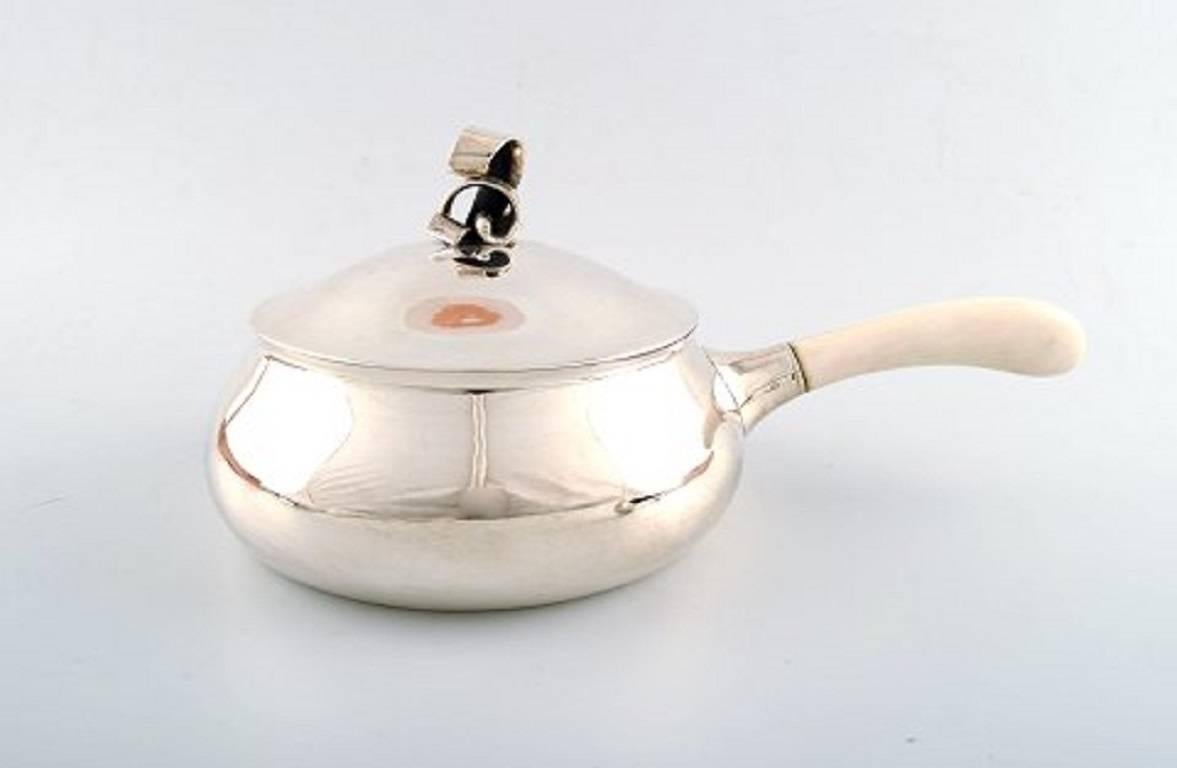 Evald Nielsen: A pair of serving bowls with cover and a sauce ladle of sterling silver. Handles of ivory.
Made and marked by Evald Nielsen anno, 1930.
Total weight 1263 gram.
Measures: Height include finial 12.5 cm. L 28.5 cm. Sauce ladle L 18.2