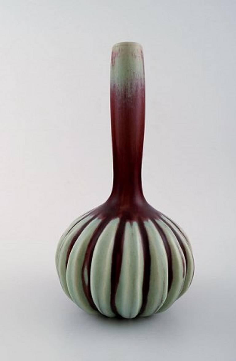 Axel Salto for Royal Copenhagen stoneware vase modelled with narrow mouth and vertical fluted pattern, decorated with oxblood glaze with green elements. 
Signed Salto. No. 20732. 
Height 23,5 cm.
In perfect condition.
3nd assortment.