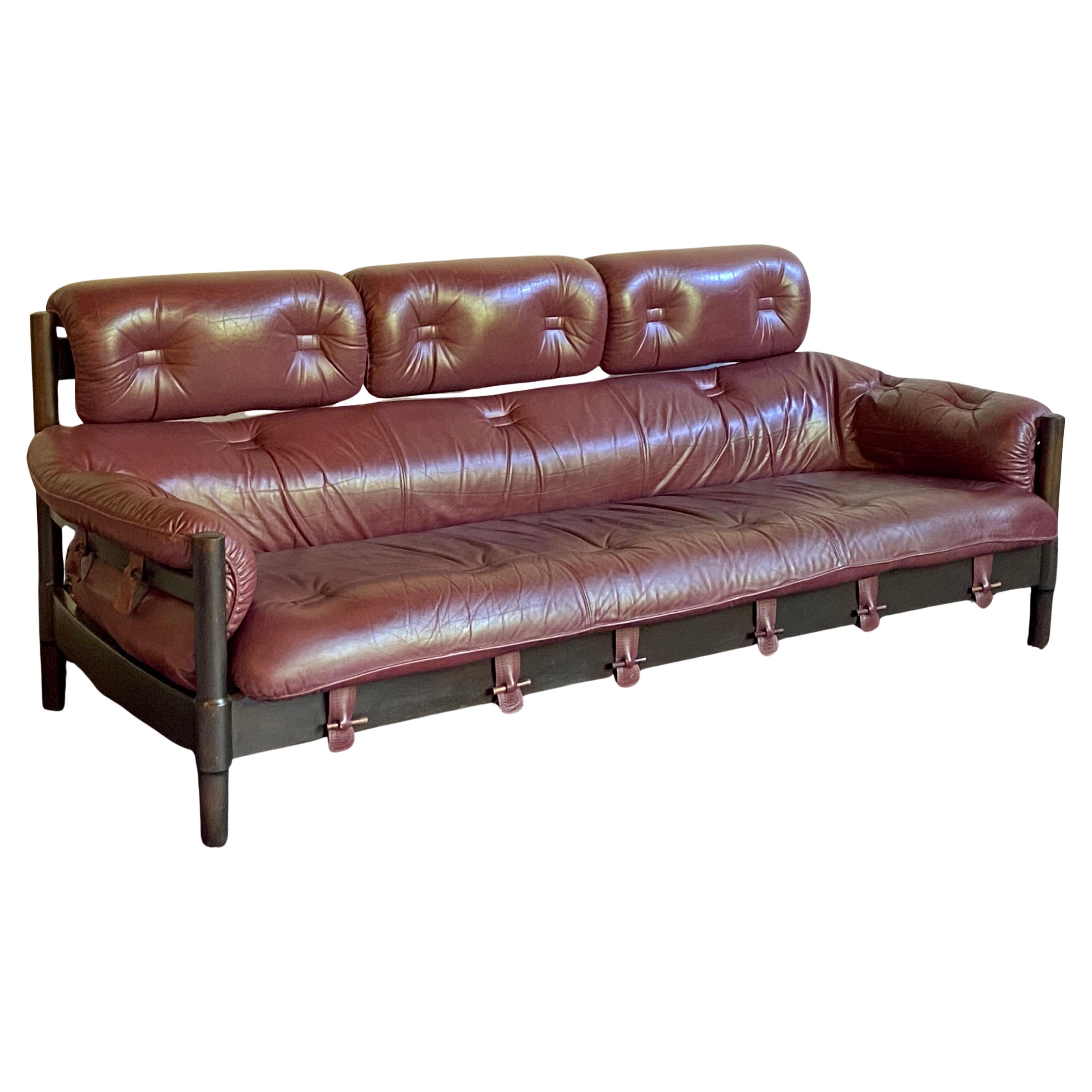 Superbe canapé en cuir de style brésilien du milieu du siècle dans une rare couleur bordeaux.
Il est doté d'un merveilleux cerclage avec des chevilles en bois qui maintiennent les coussins en place. Probablement d'origine européenne, il n'y a pas de