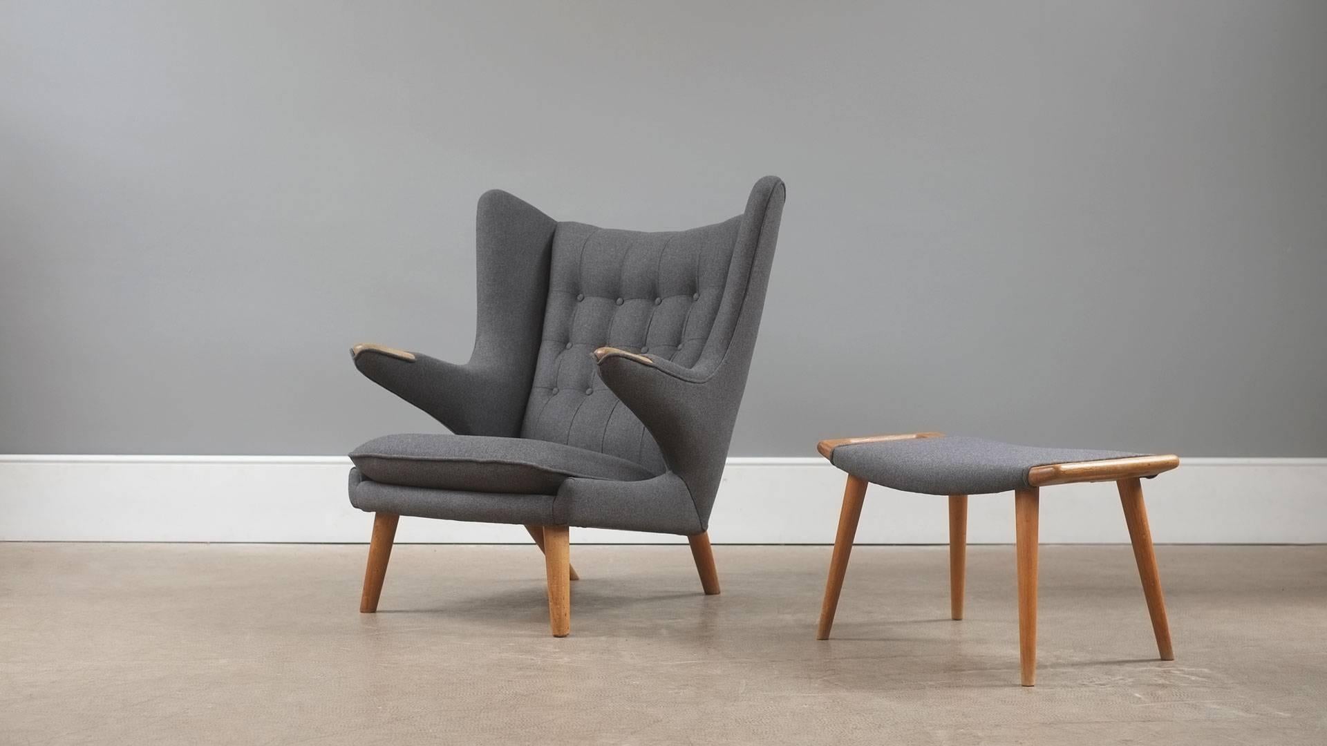 Amazing papa bear chair and footstool designed by Hans Wegner for AP Stolen, Denmark. Beautiful 1960s example with oak legs and paws. Fully reconditioned and re-upholstered in Warwick grey wool. Both pieces retaining original Danish furniture label.