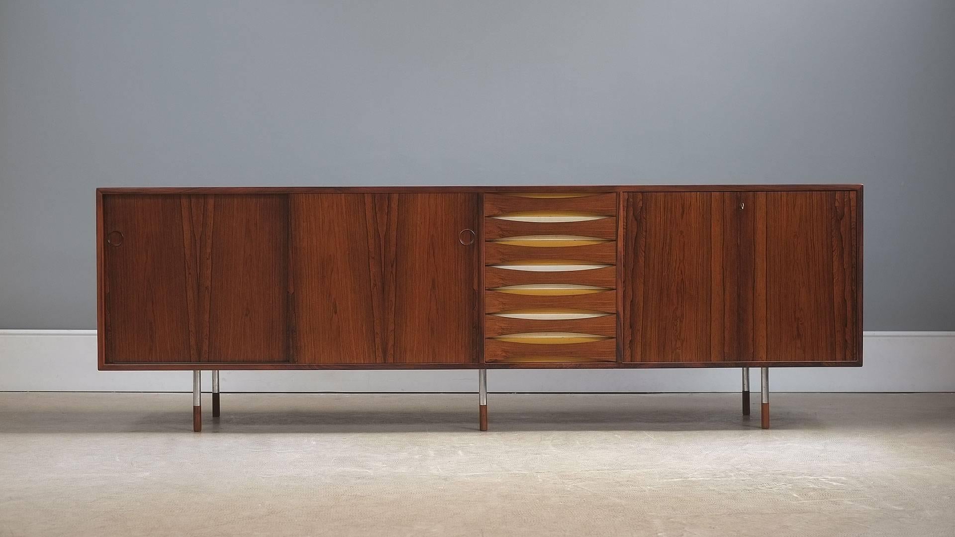Monumental ‘Triennale’ sideboard designed by Arne Vodder for Sibast, Denmark. The rarest and best of all the models in this series with steel legs and rosewood tips, reversible doors with original paint and painted draw detail. Staggering piece in