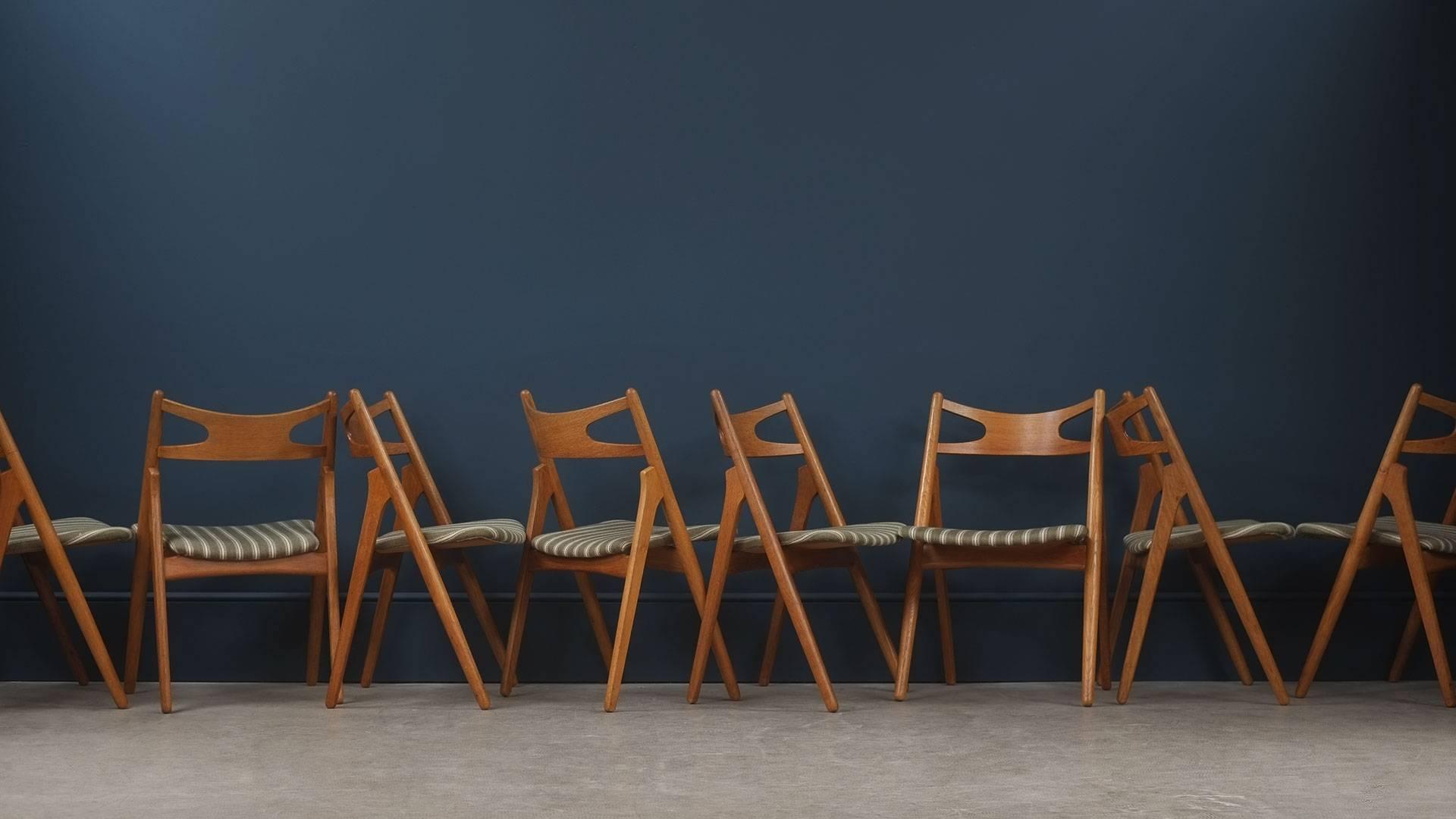 Set of eight CH29 or sawback dining chairs designed by Hans Wegner for Carl Hansen, Denmark. Early production chairs in beautiful solid oak with wollen striped fabric. Alternative upholstery options available at request.