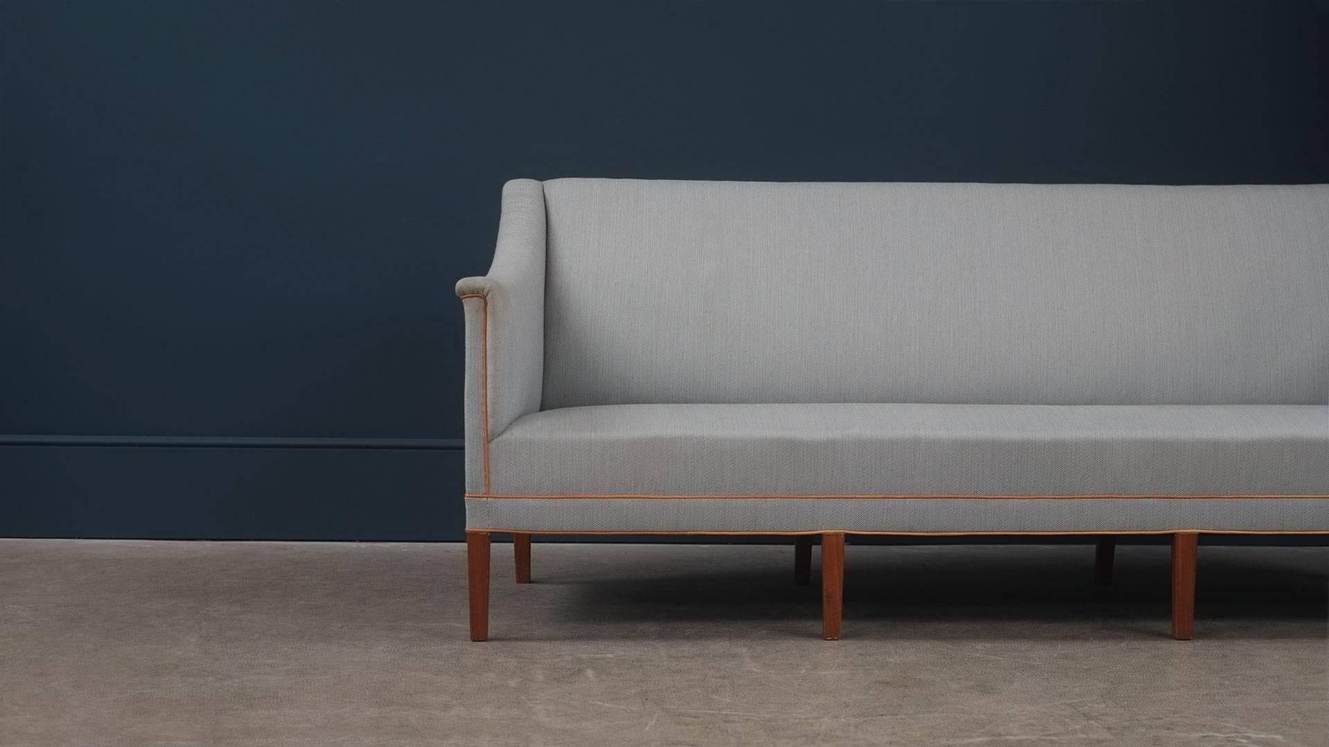 Amazing sofa designed by Kaare Klint for rud. Rasmussens Snedkerier, Denmark, 1941. Ultra elegant and super high quality piece with eight solid teak legs. This example in grey/blue fabric with natural leather piping. Superb and sought after piece.
