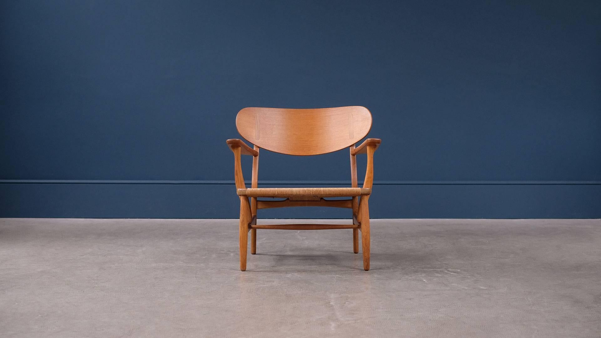 Original CH22 lounge chair in solid oak with papercord seat designed by Hans Wegner for Carl Hansen, Denmark. Amazing example of this beautiful lounge chair with very striking grain and superb exposed joint detail. Great piece.