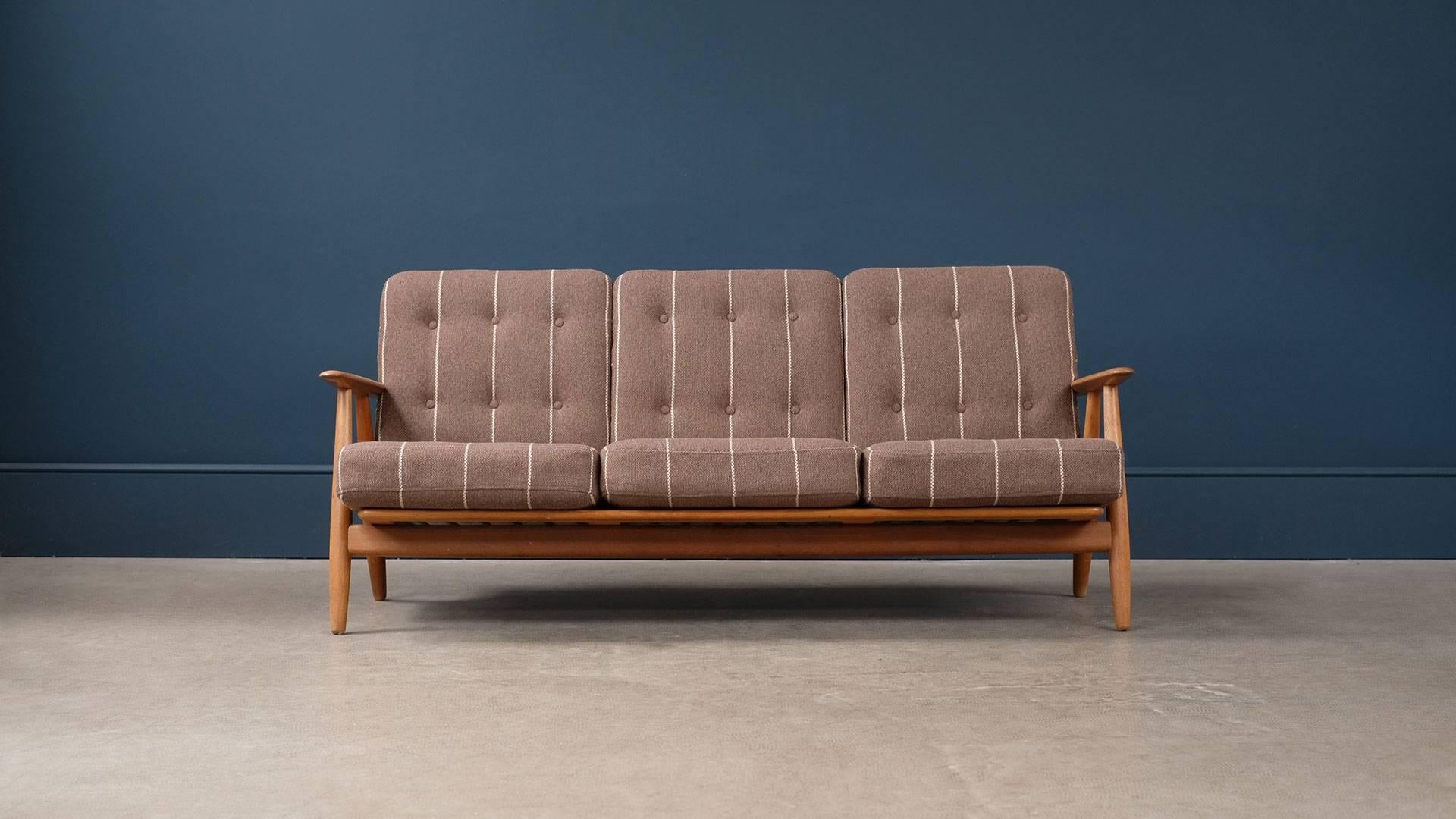 Beautiful GE240 cigar sofa in solid oak designed by Hans Wegner for GETAMA, Denmark. Great example in solid oak with staggering grain pattern to the arms. Original internally sprung cushions with beautiful striped fabric. New fabric options also