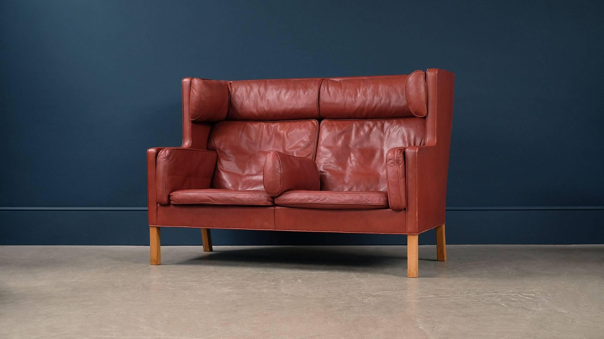 Amazing two-seat coupe sofa model 2192 designed by Børge Mogensen for Fredericia, Denmark. Unsurpassed quality in beautiful patinated thick red / brown leather with solid oak legs. Wonderful and rare sofa.