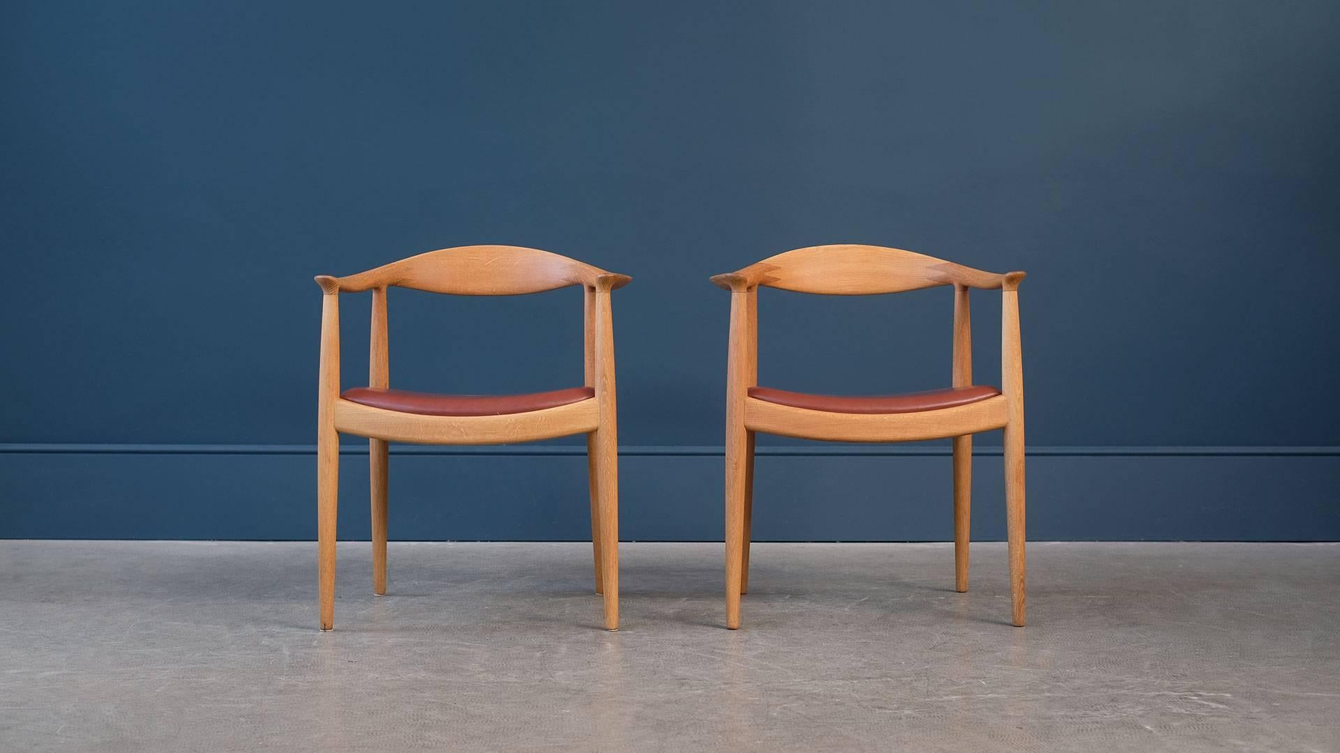 Pair of round chair in oak designed by Hans Wegner for cabinet maker Johannes Hansen, Denmark. Fabulous quality, details and ultra elegant design. This examples with new analine leather seat. The most famous of all Wegner pieces.