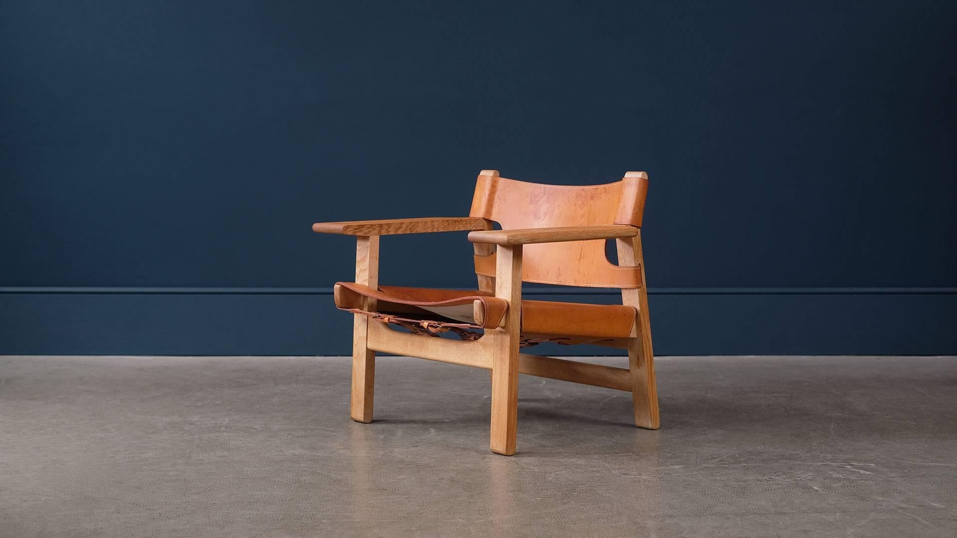 Fantastic Spanish chair designed by Børge Mogensen for Fredericia, Denmark. Wonderful example with exceptional figured solid oak frame and lovely patina to the cognac colored saddle leather seat and back.