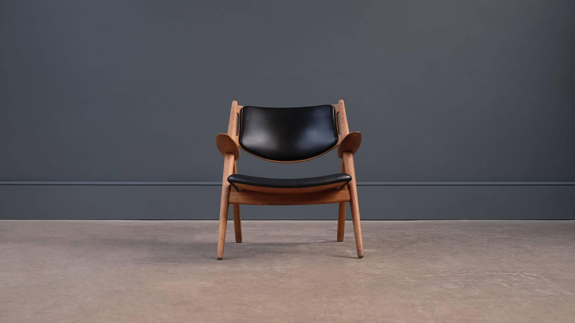 Amazing first production CH28 or Sawback lounge chair designed by Hans Wegner for Carl Hansen, Denmark. Early chair in oak with beautiful black leather. Superb grain detail.