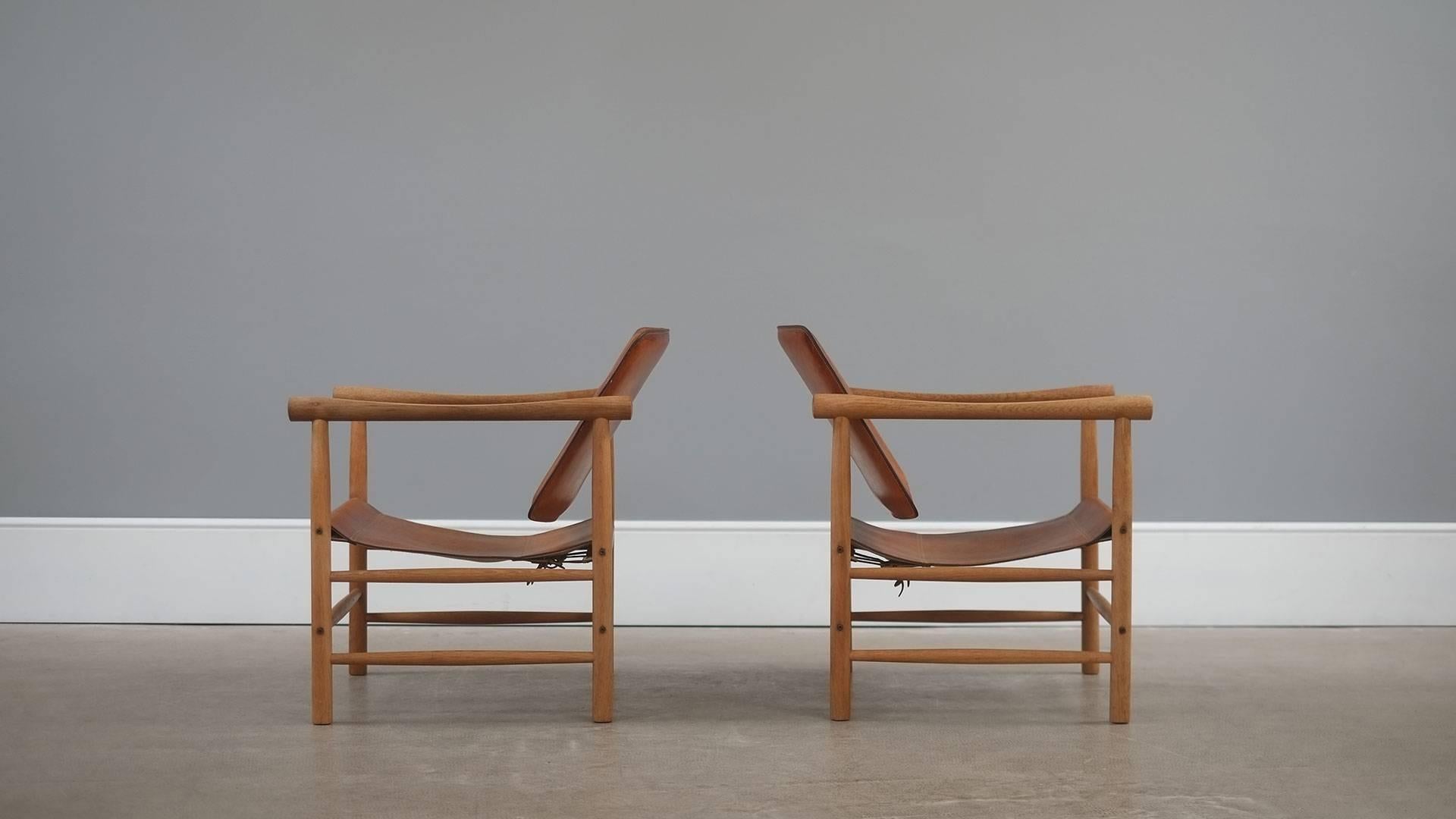 Amazing pair of rare Safari armchairs in solid oak with stitched saddle leather seats and backs designed by Kai Lyngfeldt Larsen for Soborg Mobler, Denmark. Wonderful chairs with perfect patina.