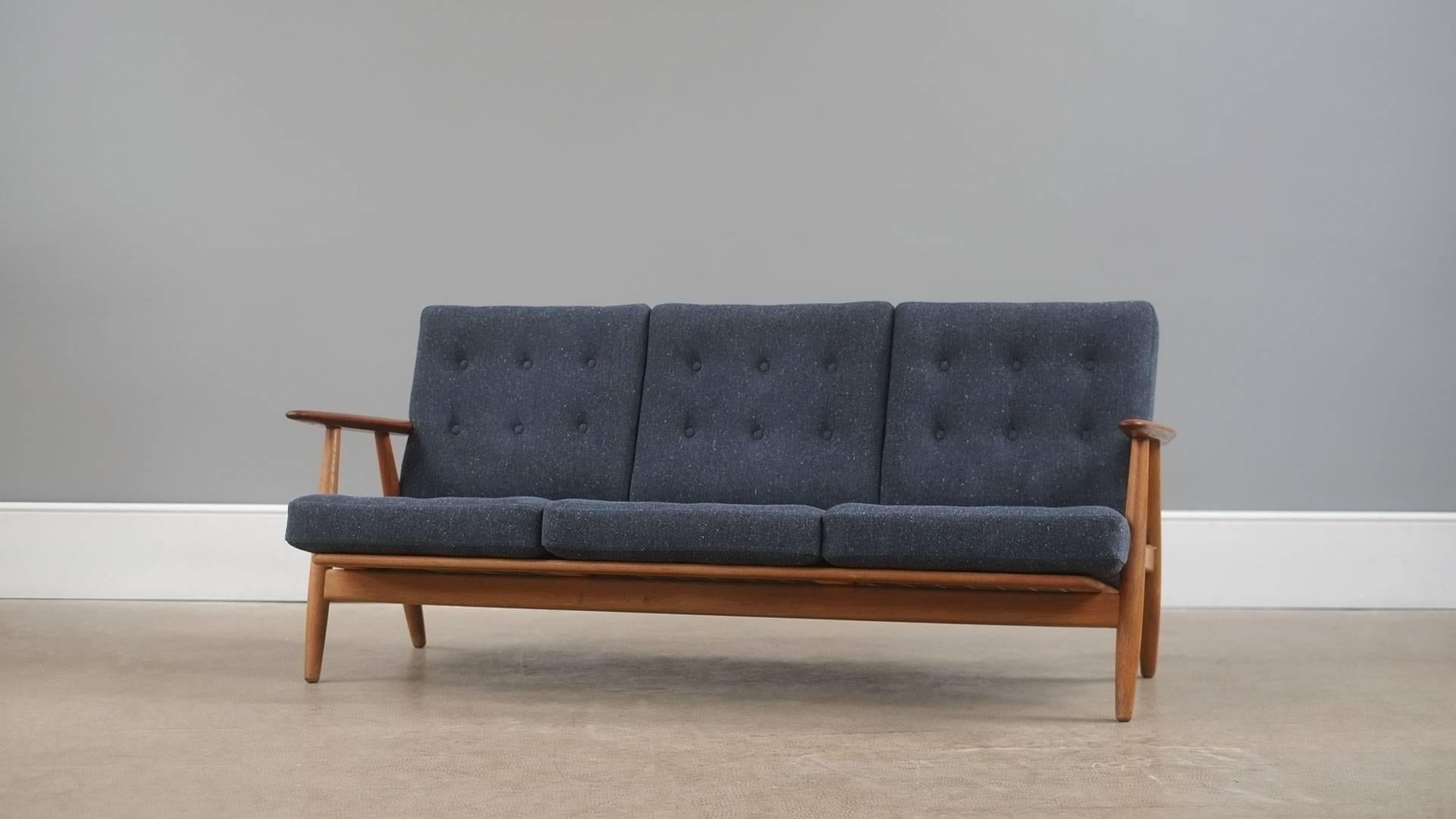 Wonderful Cigar sofa by Hans Wegner for Getama, Denmark. Solid oak frame with contrasting teak arms.  Fully reconditioned original sprung cushions with new Fleck ink upholstery. Matching chair available.
 
 