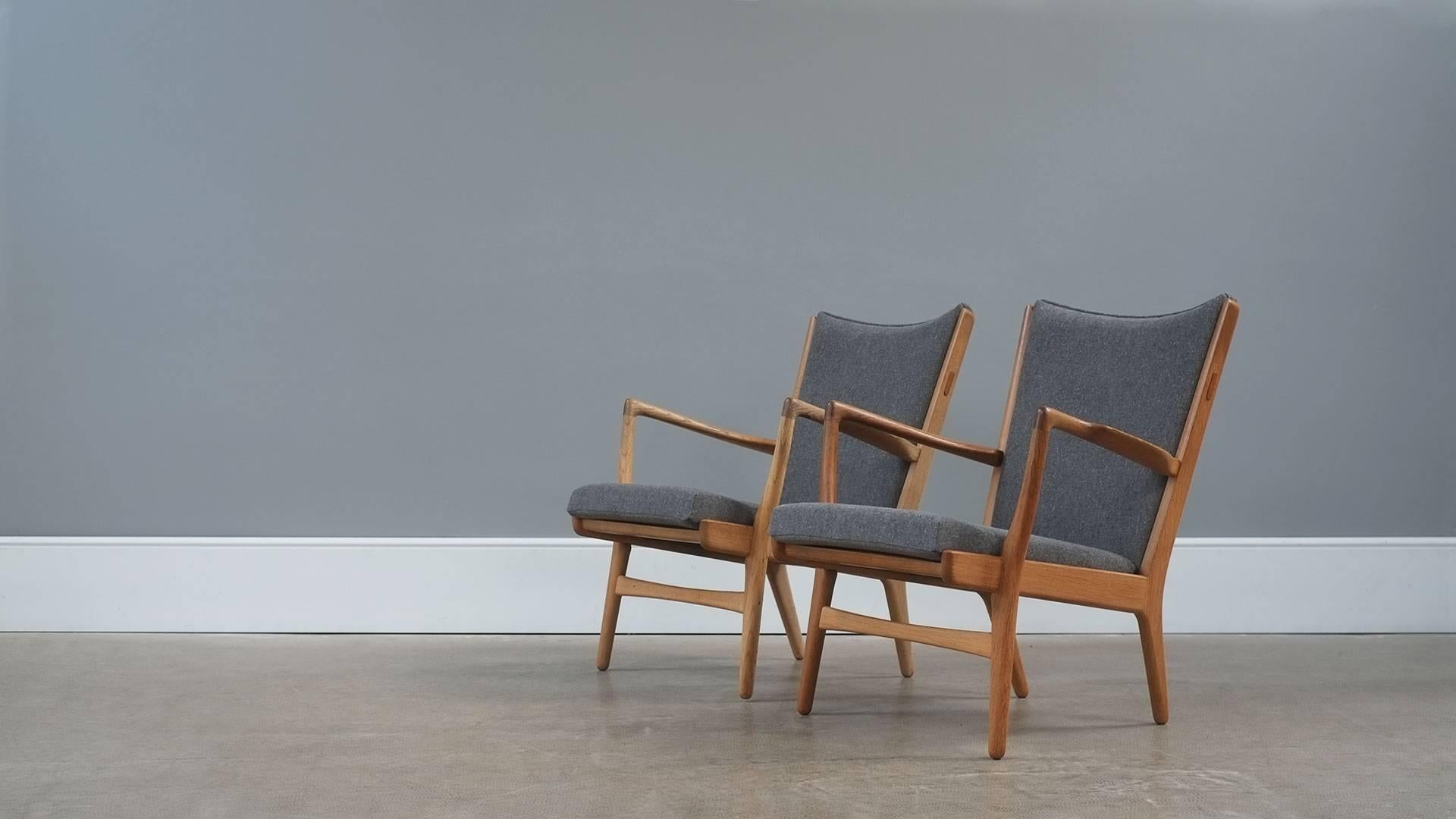 Amazing original pair of rare AP16 lounge chairs in solid oak designed by Hans Wegner for Cabinetmakers AP Stolen, Denmark. Fully reconditioned and re-upholstered in beautiful grey ‘Fleck’ fabric. Wonderful chairs.