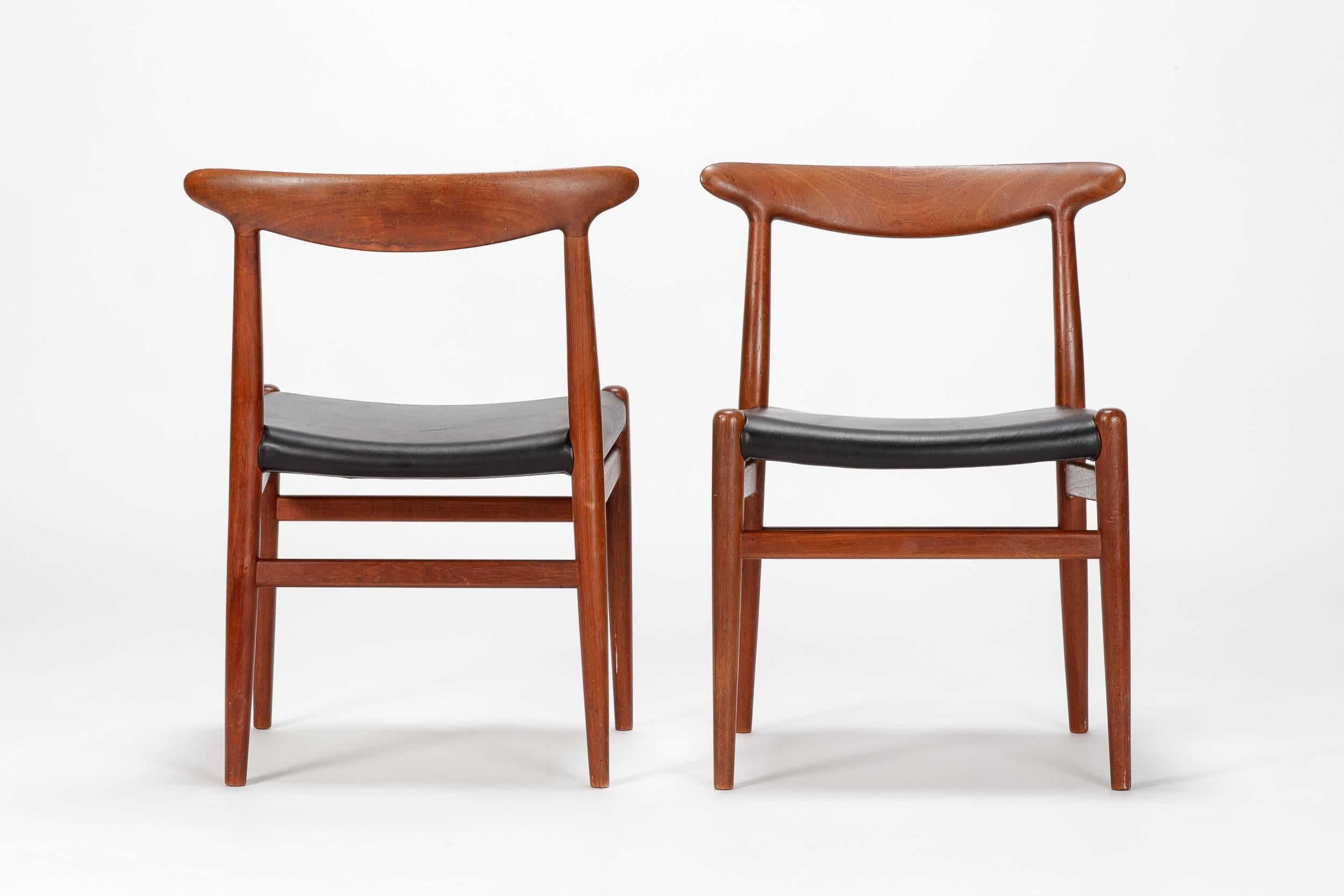 Pair of Hans Wegner chairs, model W2 designed in 1953 and manufactured by C.M. Madsen in Denmark. The frame is made of solid teak wood, the seat covers are made of soft leather. Very typical Wegner shape with round organic elements, solid