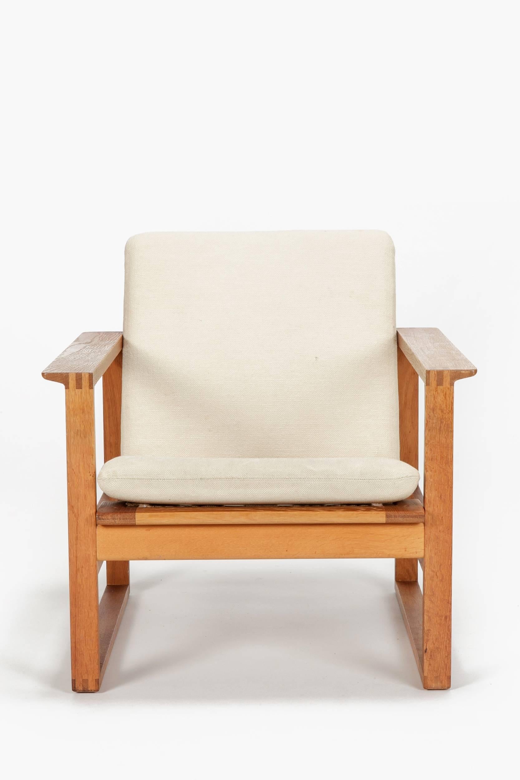 A single Borge Mogensen lounge chair designed in 1956 model No 2256 for Fredericia, manufactured in the early 1960s. Cubical frame made of solid oak with finger joints, original cushions in a cream colored linen fabric. The seat cushion can be fixed