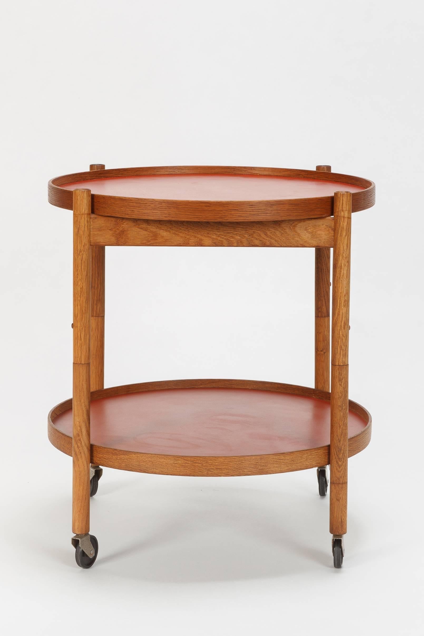 Lovely Hans Bølling bar cart designed in 1963 and manufactured by Torben Ørskov. The frame is made of solid oak, this model features two double sided trays, one has a red lino surface and the other a black. This tray table was designed after a