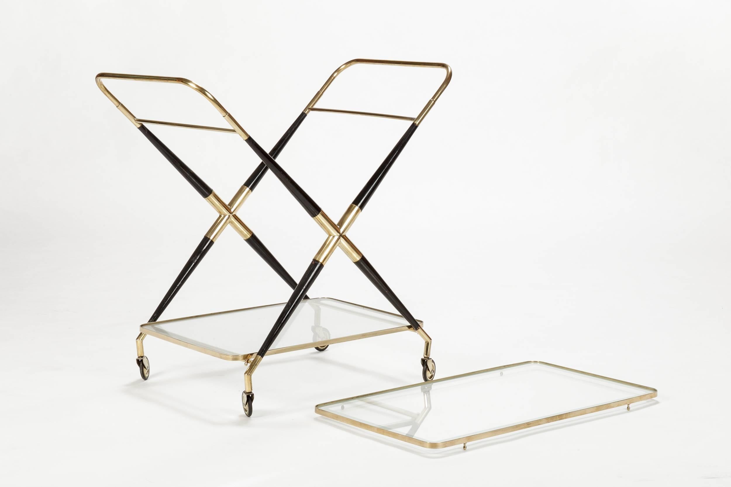 A stunning Cesare Lacca bar cart, manufactured in Italy in the 1950s. Very elegant and reduced form with a frame of solid brass and shiny lacquered black mahogany, shelves are made of glass with etched borders. The glass shelves can be removed to