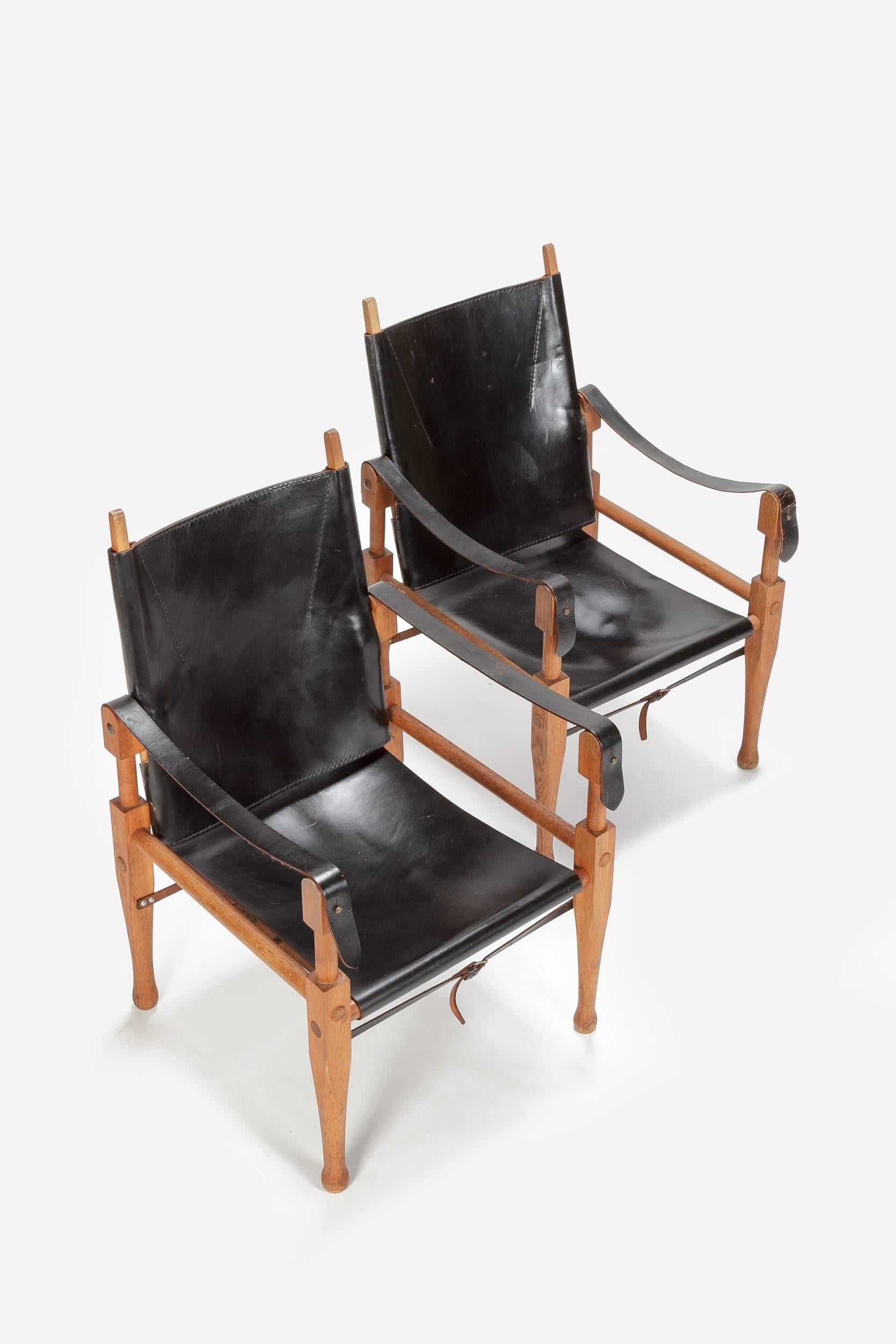 Pair of Wilhelm Kienzle safari chairs designed in 1928 produced in the 1950s by Wohnbedarf Zurich in Switzerland. Frame is made of solid oak, original black leather with a very nice patina, brass screws! Completely dismountable.