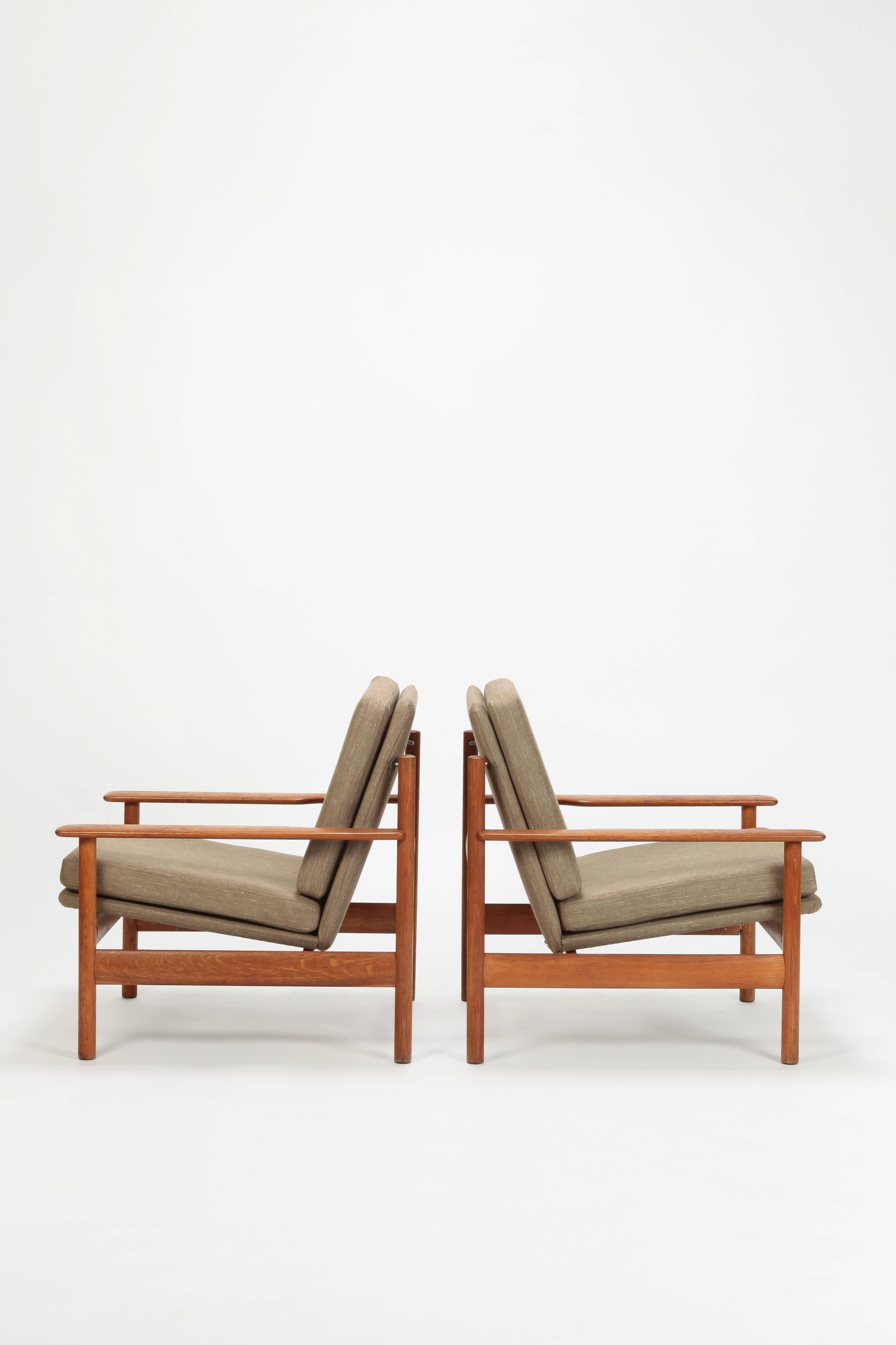 Pair of Sven Ivar Dysthe chairs manufactured by Dokka Mobler in the 1950s. Solid oak frame. Newly upholstered with linen. Classically sleek design combined with pure comfort. The generously sized armrests and the swinging seat invite you to stay a