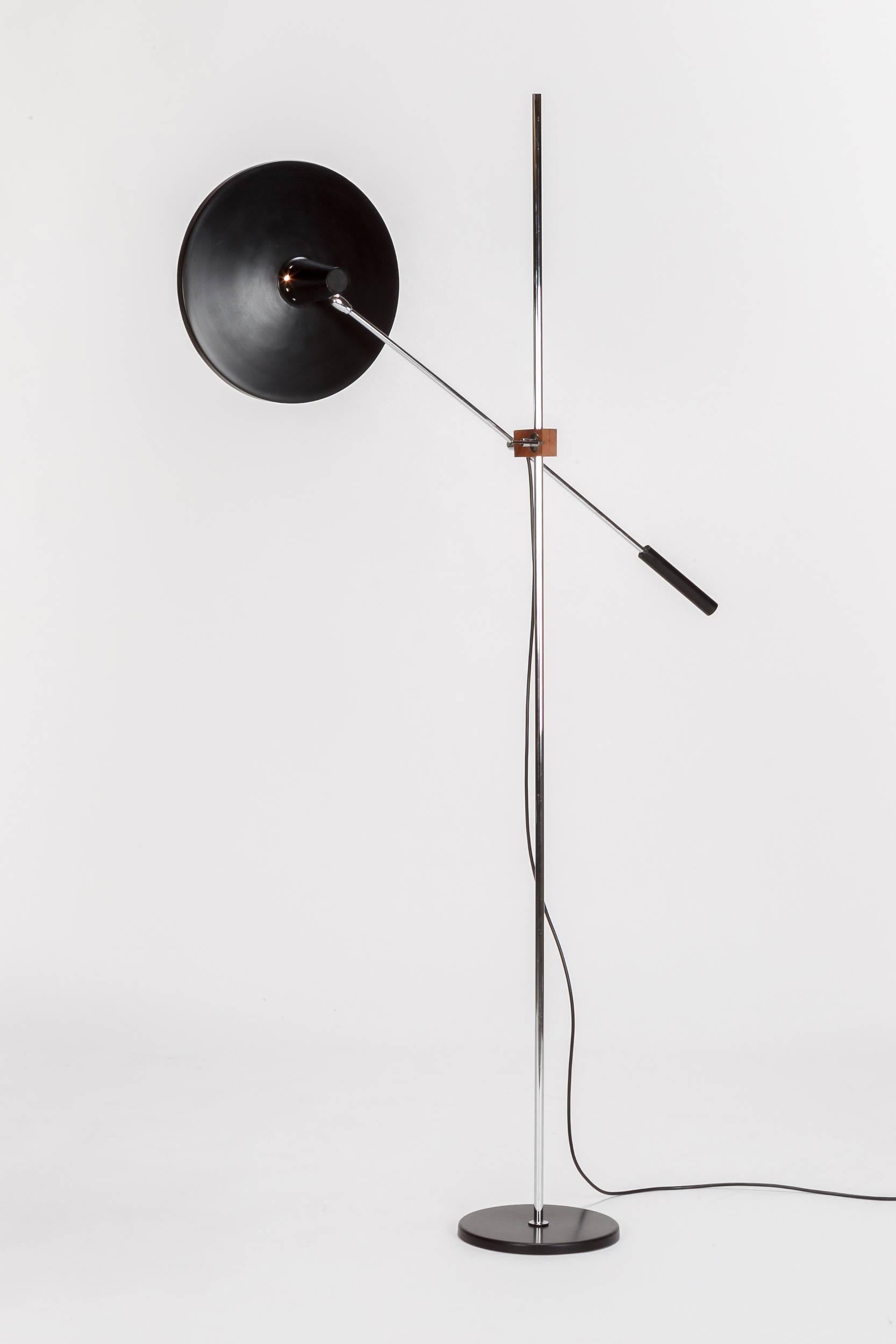 A stunning Swiss floor lamp in the manner of the famous Rico & Rosemarie Baltensweiler lamp, this model was manufactured in the 1960s in Switzerland. Adjustable in height with a wooden walnut clasp. Very well-propotioned as well as practical.
