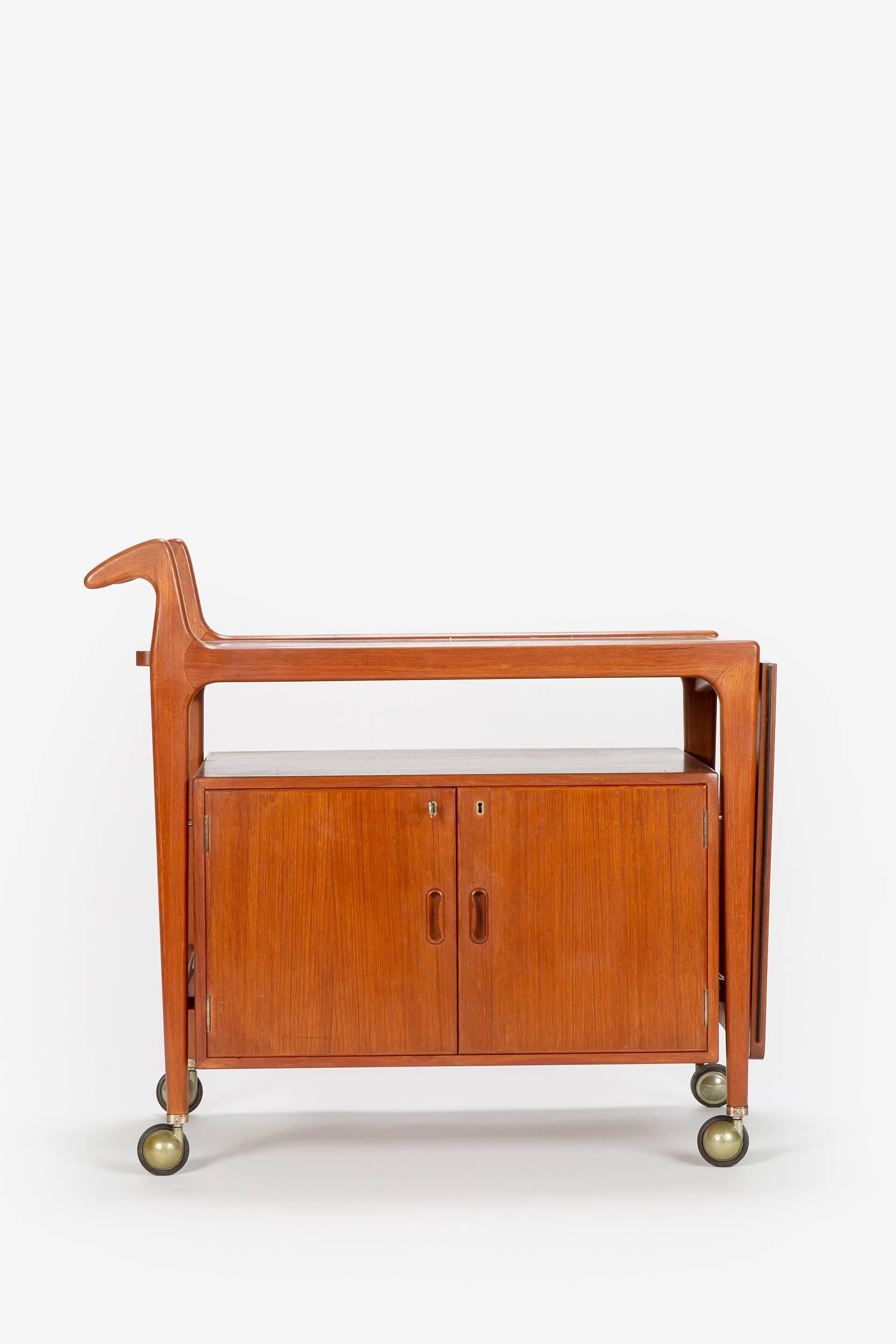 A very unique bar cart by the Danish manufacturer Falster Mobelfabrik in the 1960s. Organically shaped handles, top shelve has a black Formica surface and can be fold up and down, bar cabinet with original key.
Measures 142cm when extended, the