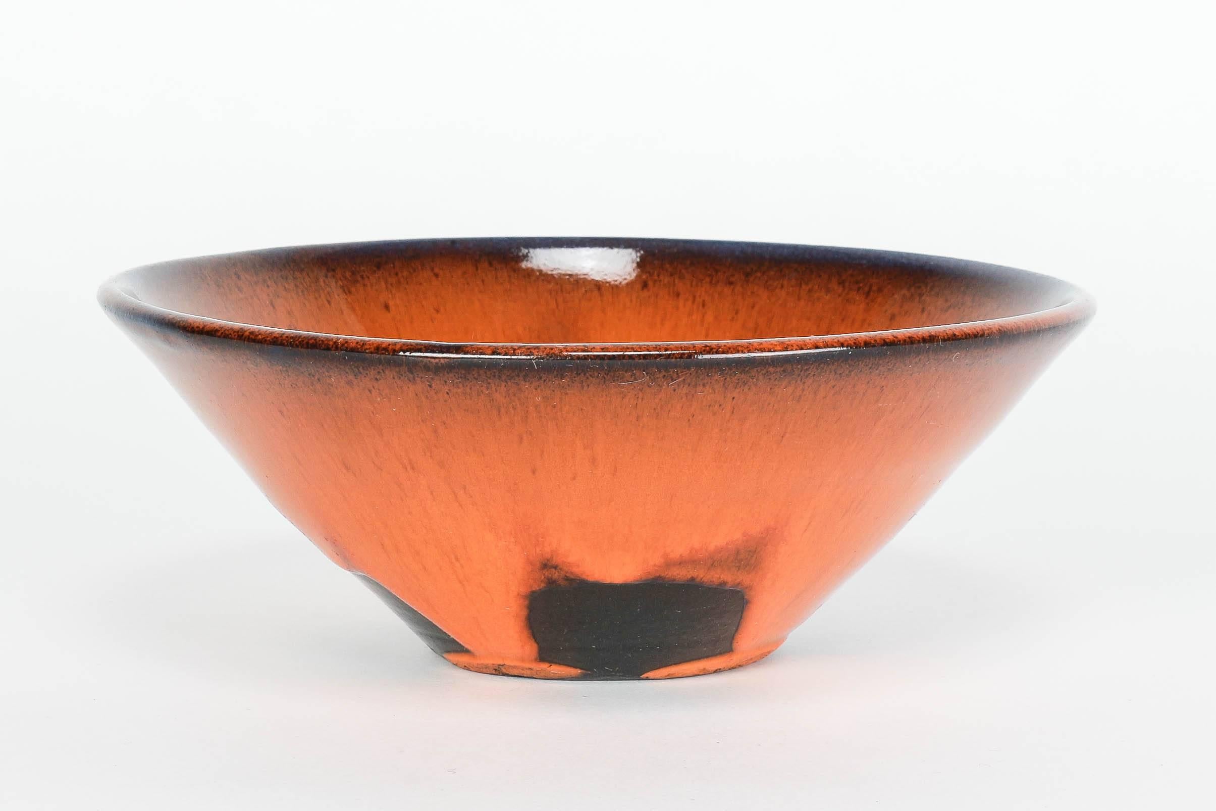 Beautiful Swiss pottery bowl in orange and black colors with a dash of blue on the rim. Signed to bottom with “RE”.