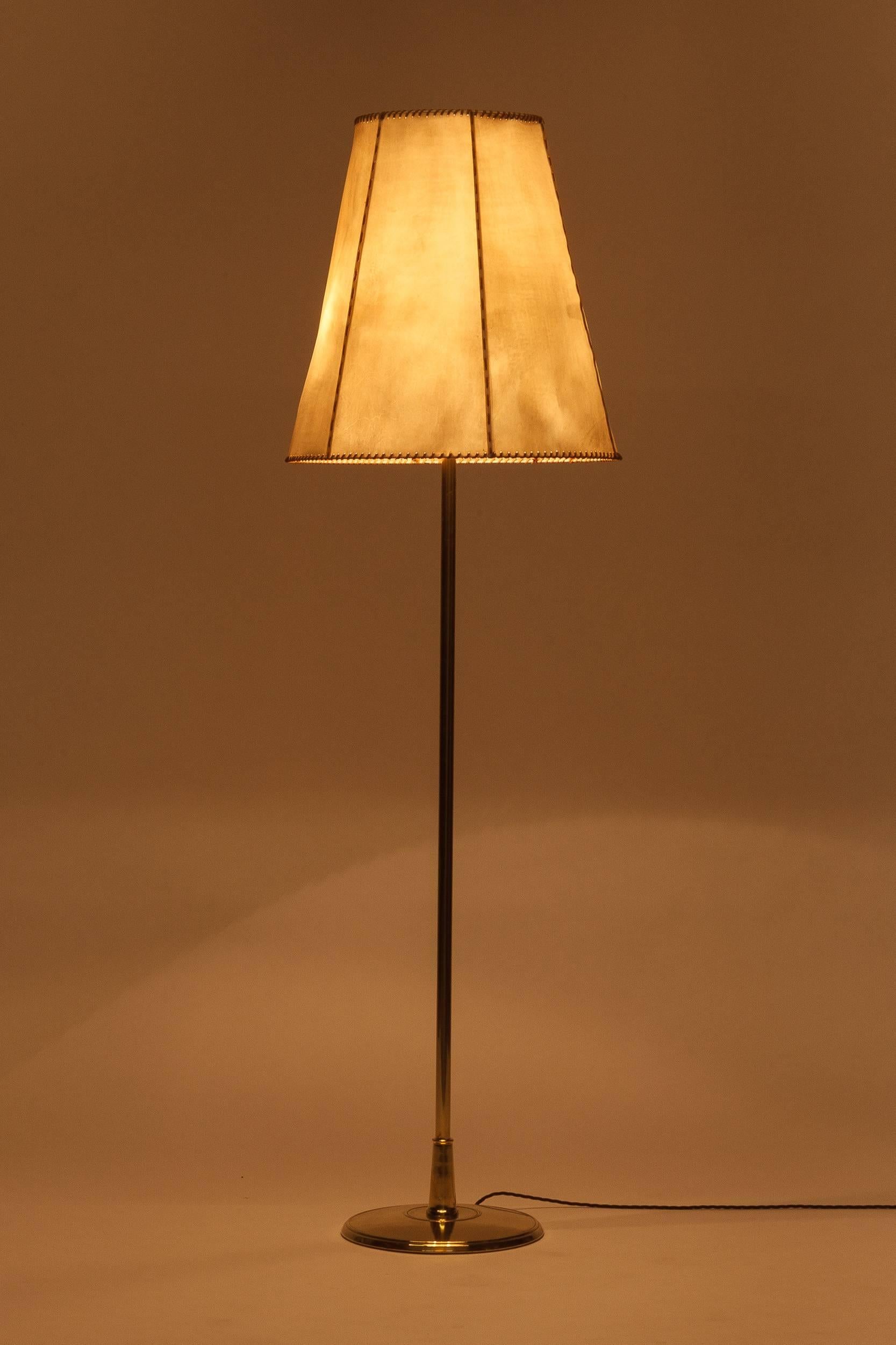 Swiss floor lamp model 454 manufactured by Eberth in Zurich in the 1940s. Beautiful original shade made of cow hide with a buckskin ribbon on the border. One uplight and two bulbs to illuminate the shade. The stem is made of brass, newly polished,