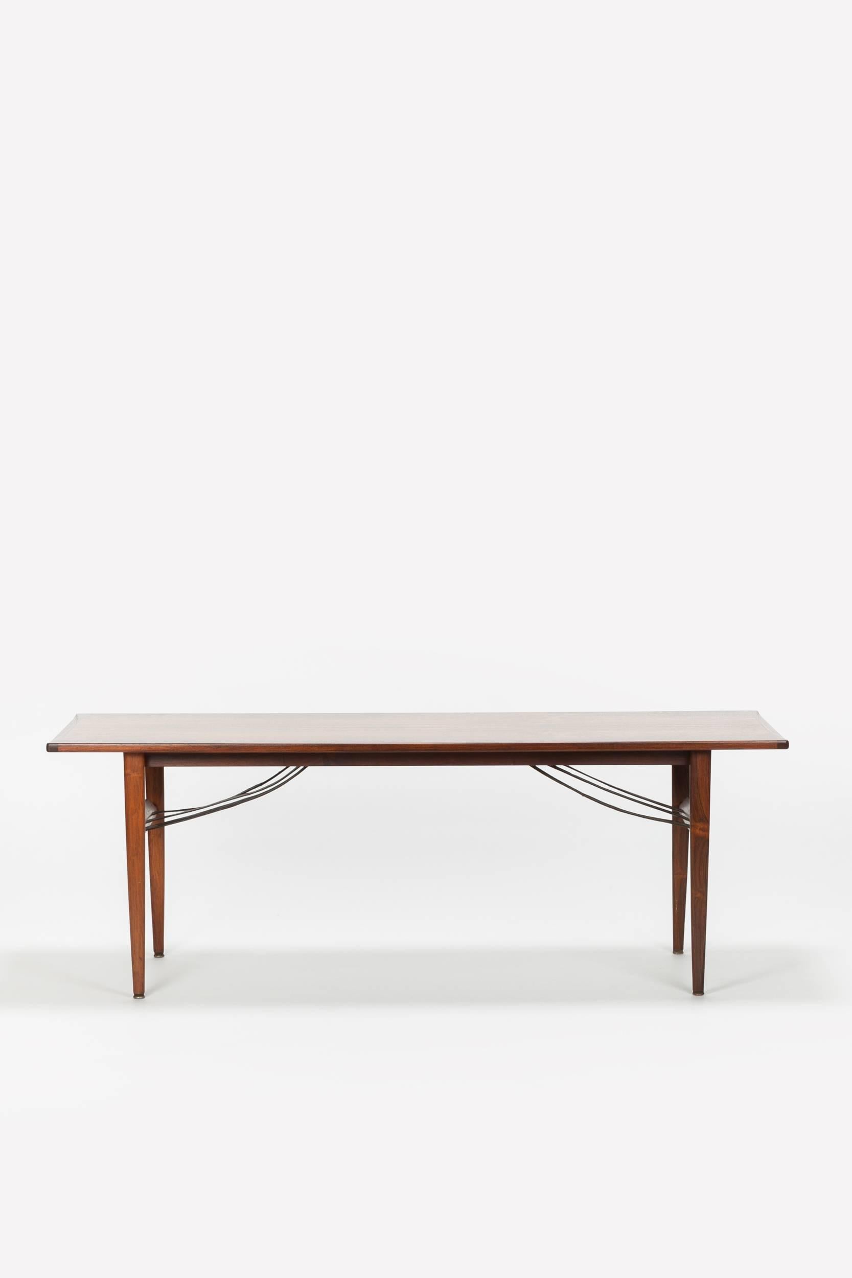 Very nice solid rosewood coffee table from the 1960s, manufactured in Denmark. A particularly beautiful detail are the leather straps which serve as a newspaper rack.