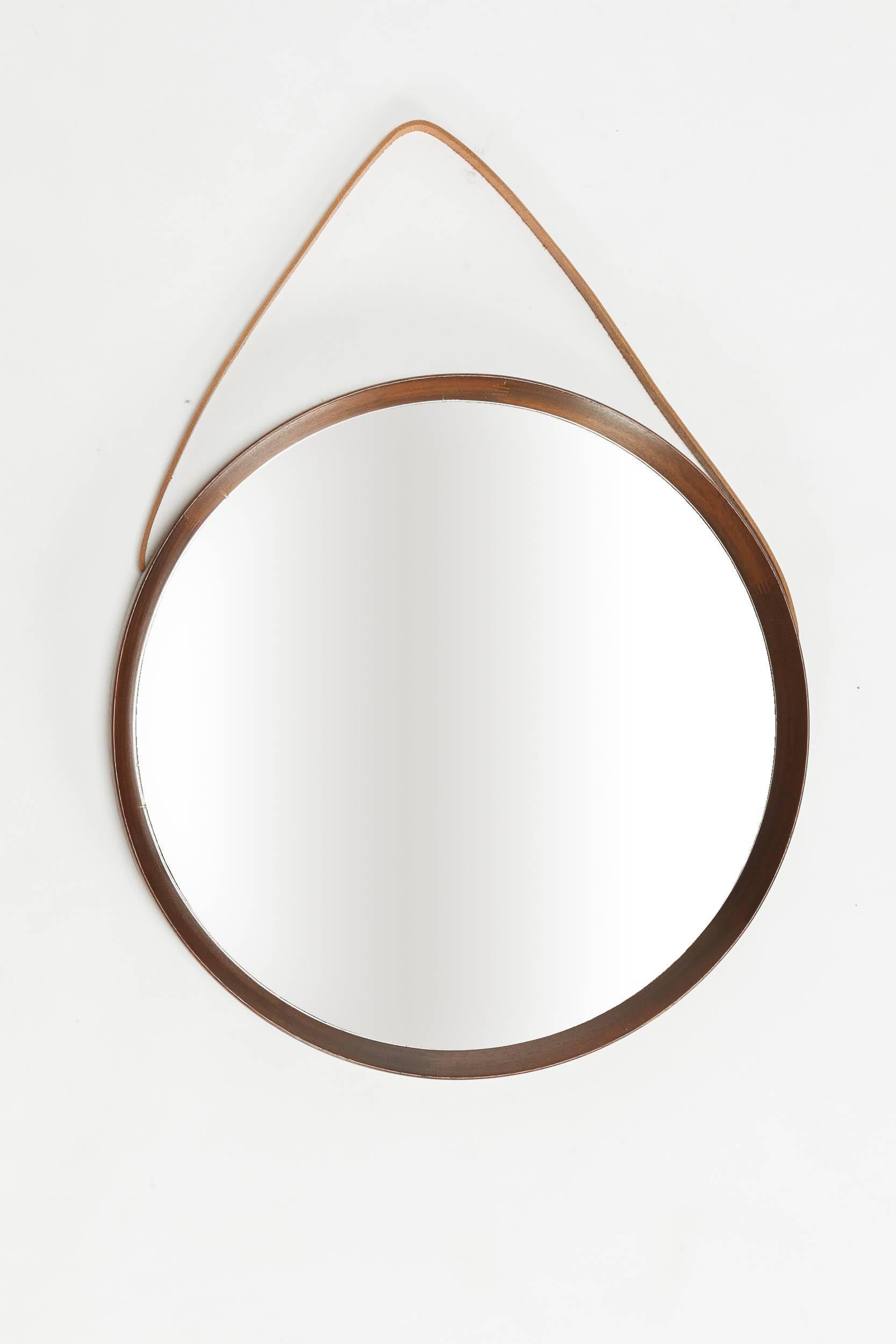 Stunning Swedish mirror designed by Uno & Östen Kristiansson and manufactured by Luxus Vittsjö in the 1960s. The mirror is bordered by a solid teak frame with a leather strap to wall mount.