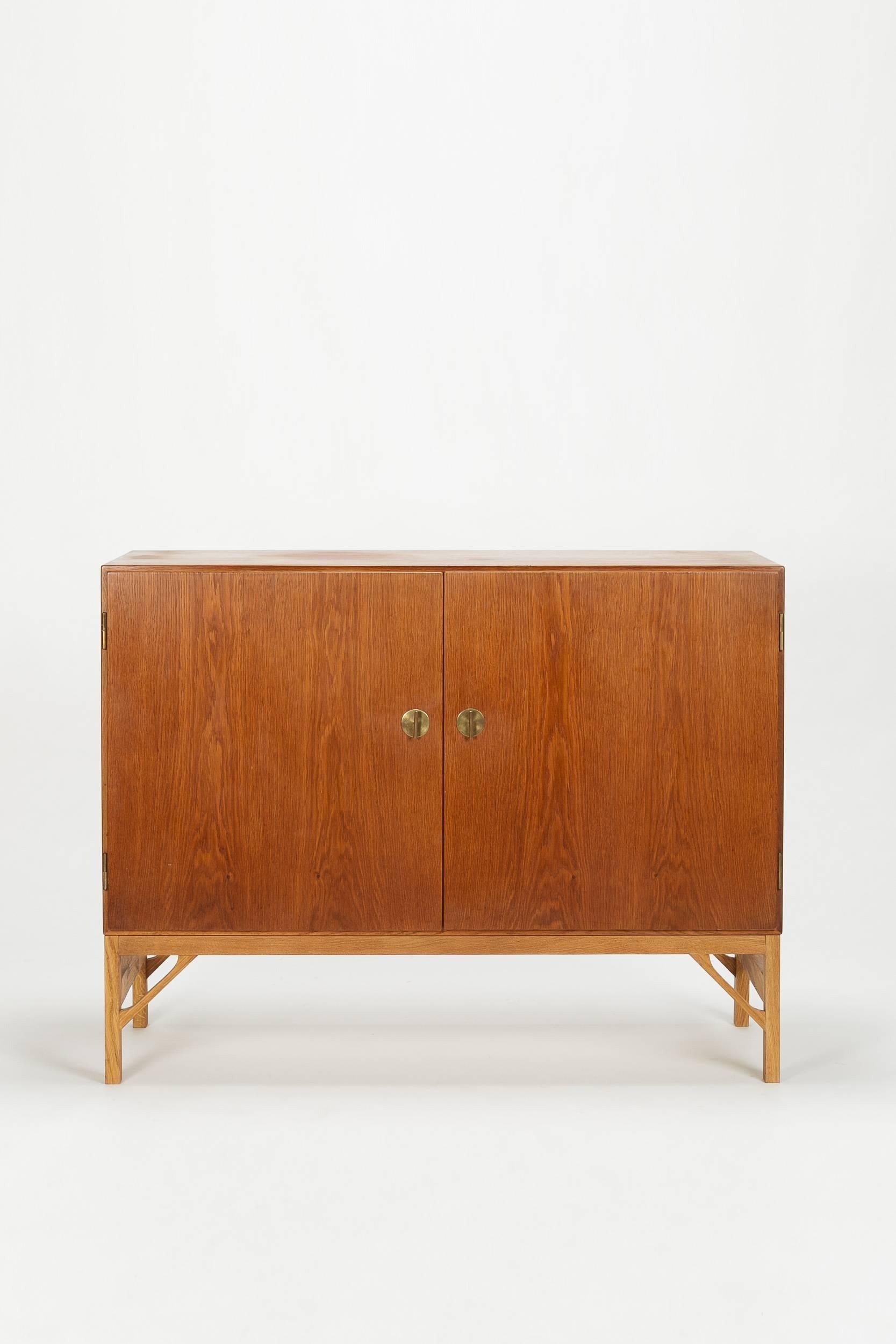 Gorgeous Børge Mogensen highboard A232 manufactured by FDB Mobler Denmark in the 1950s. Beautiful combination of teak (corpus) and finely wrought oak (base), brass fittings. High quality interior made of birch wood, with various adjustable shelves