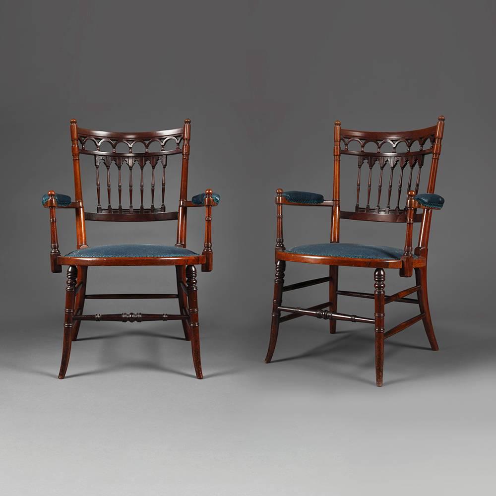 A pair of high quality Victorian rosewood armchairs with pierced and shaped back support with arched and columned design over half crescent over stuffed arm supports framing a central seat pad on turned downswept sabre legs.