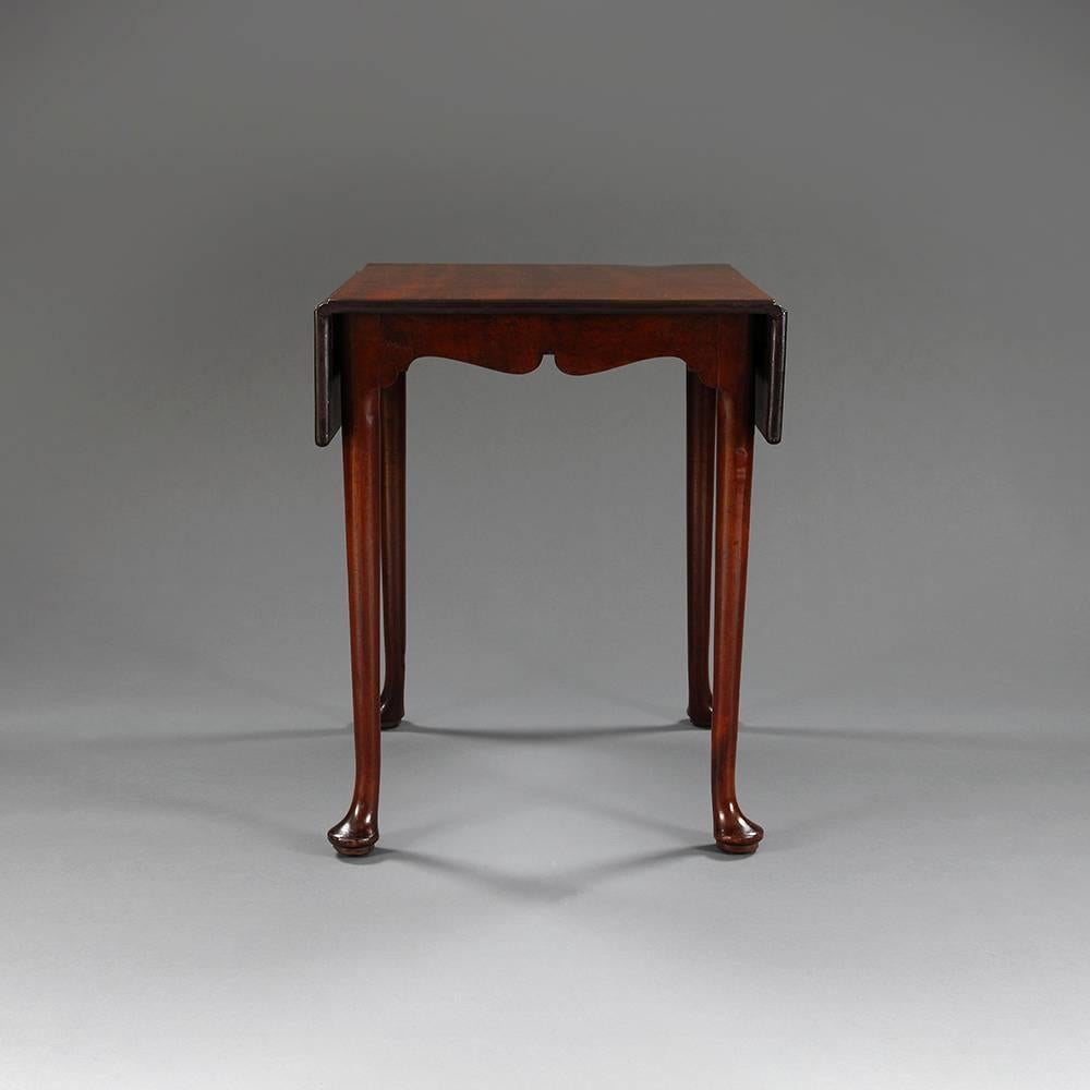 A George II mahogany table with two drop-leaf sides over shaped apron on cabriole legs terminating in pad feet.