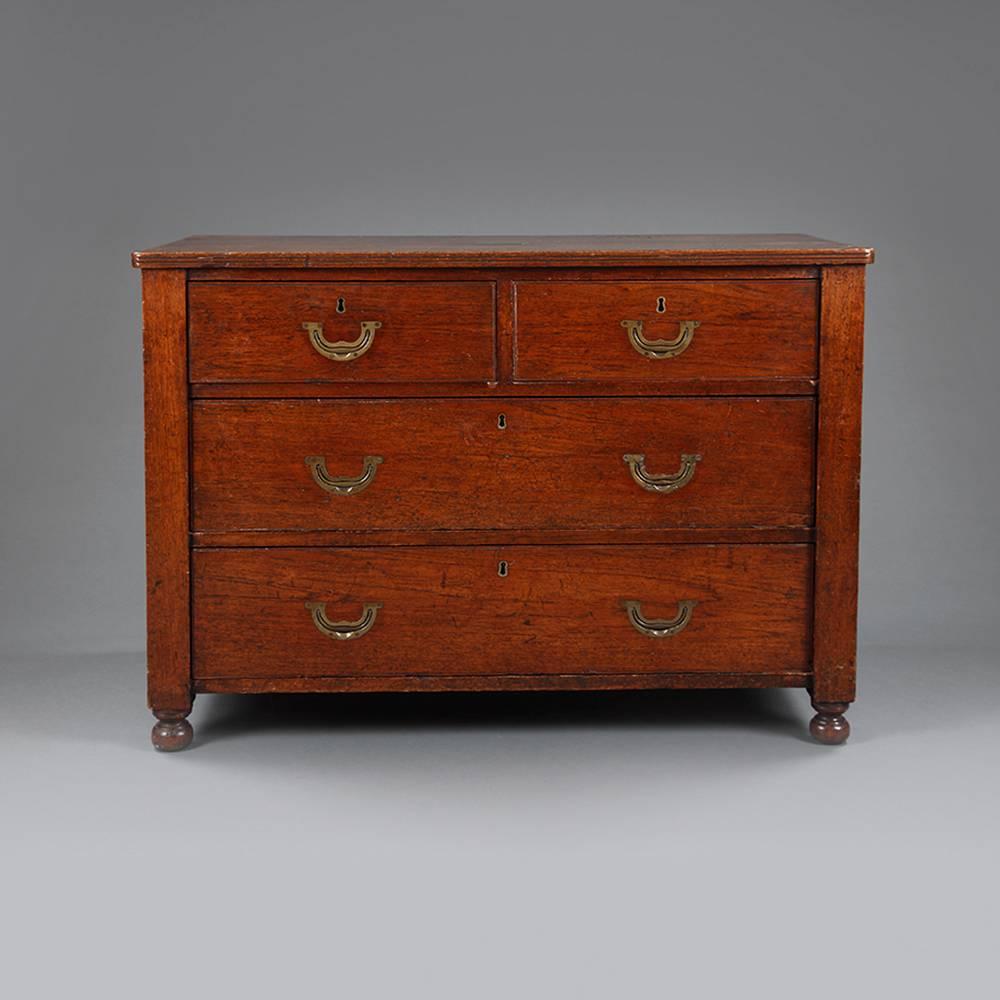 A mid-19th century teak Campaign chest with plain top of two smaller and two drawers on bun feet with inset brass handles and carry handles to the side.

The top with a brass plaque engraved "Anne Amelia Wallace".