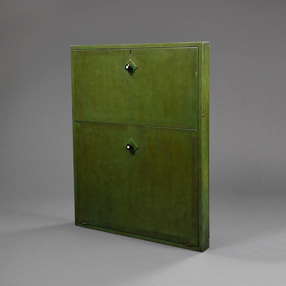 An unusual green painted wall-mounted student’s desk by the Rowley Gallery. 

The front decorated with green stippled paint and pressed rilpple borders enclosing a fitted interior to the fold down top section and storage compartment to the bottom.