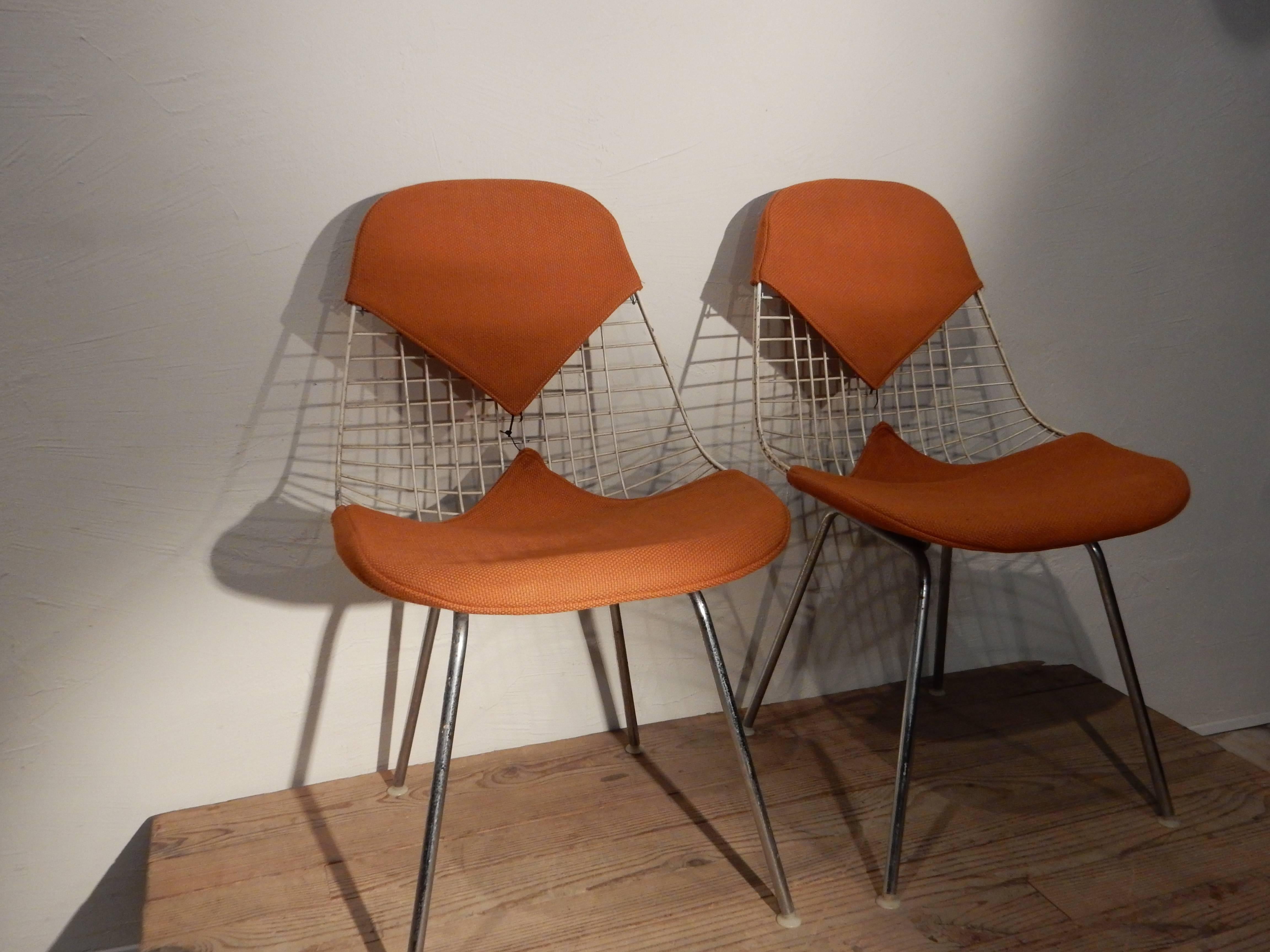 A pair of wire chairs by Carles and Ray Eames edited by Herman Miller, circa 1960 with original orange upholstery.