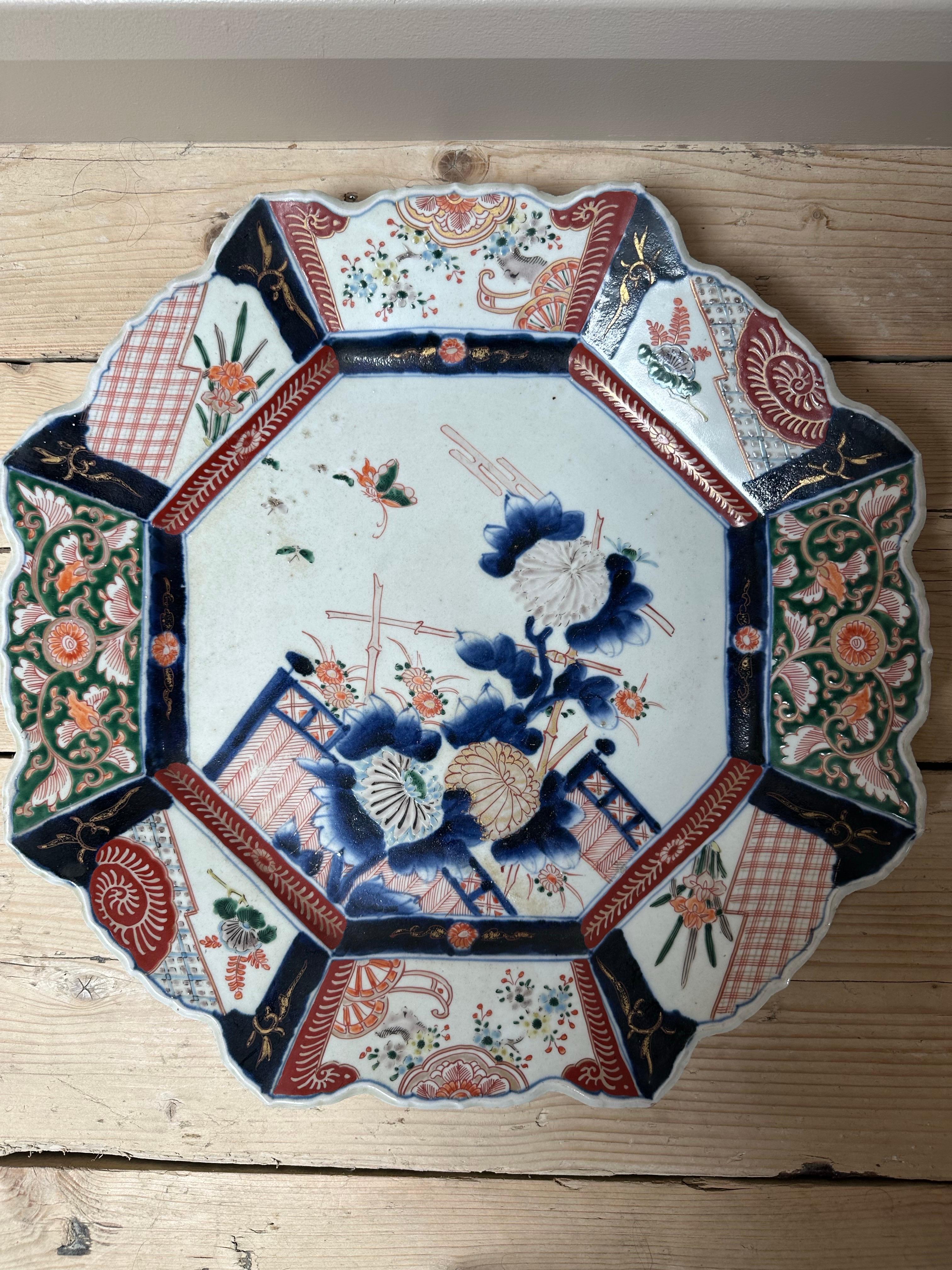Cet exquis plat en porcelaine Imari du XIXe siècle présente une forme octogonale peu profonde, richement décorée de pivoines, d'insectes et de panneaux floraux peints à la main. Magnifique exemple du style Imari, il met en valeur le savoir-faire