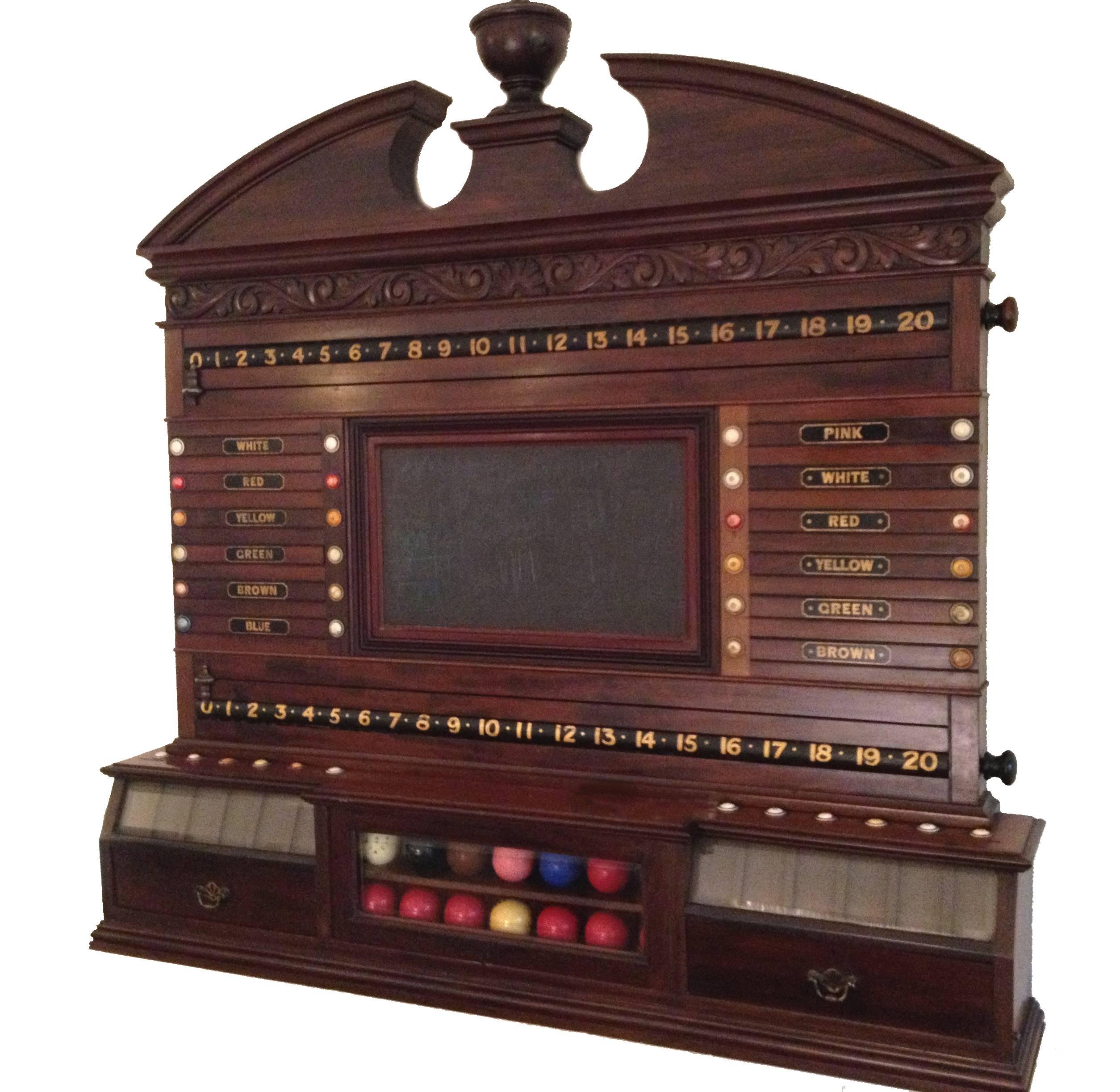 This beautiful wall-mounted mahogany scoring cabinet was made circa 1880, it features a decorative carved pediment, a central reversible mirror panel flanked by Life pool sliders and revolving number bars, all mounted on a ball storage box with