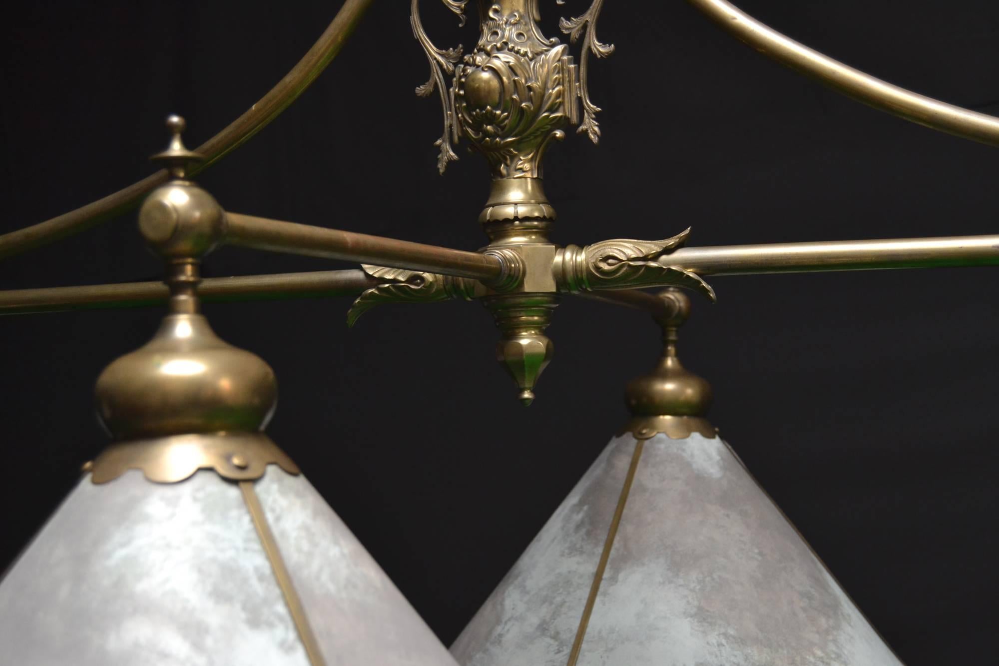 This unique brass framed antique billiard light was made by the London firm Burroughes & Watts, circa 1895, it features a central upright adorned with foiliate castings and curved braces embellished with brass collars and coronets.

The