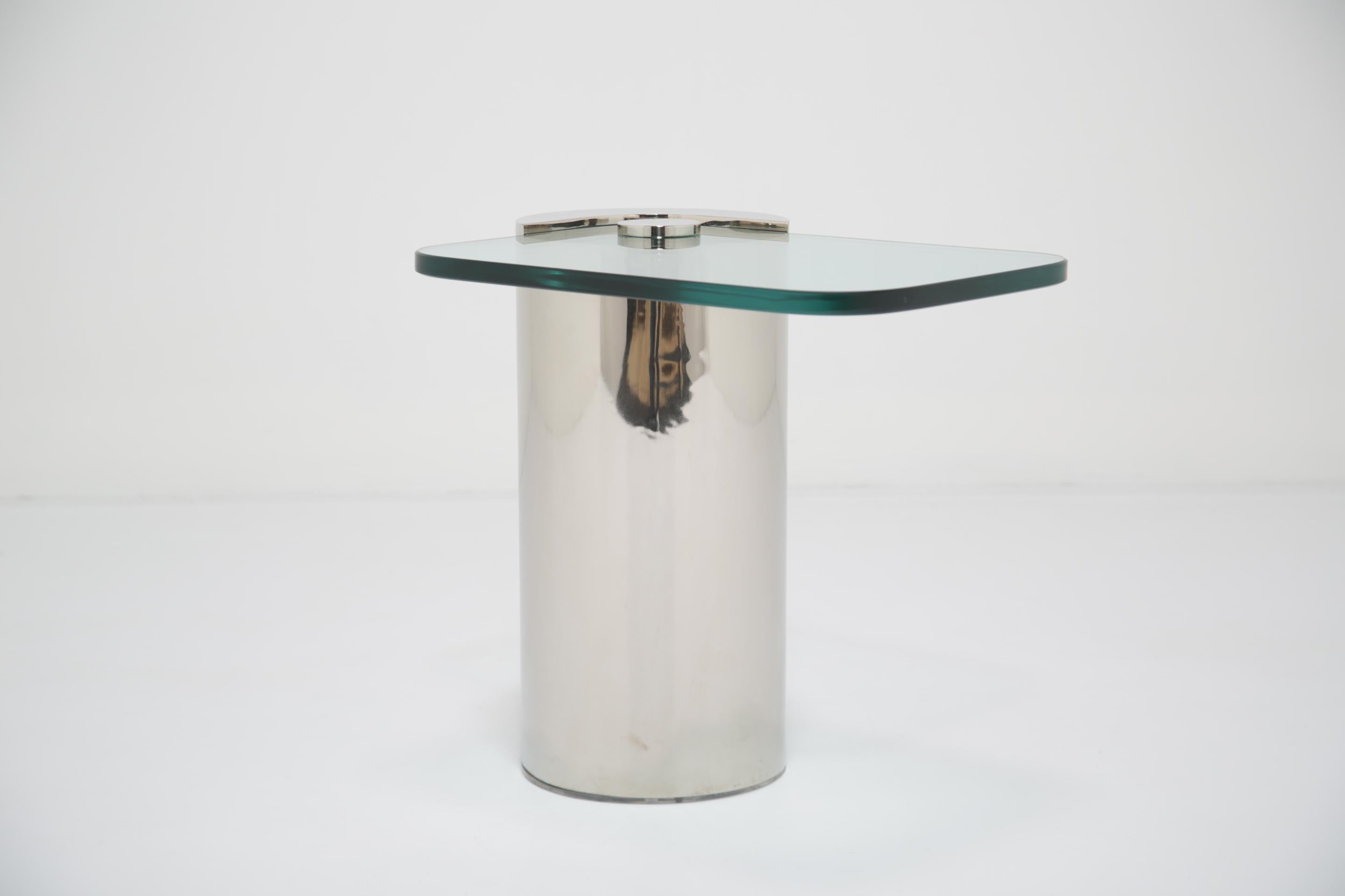 Cette table à cocktail de style Karl Springer est caractérisée par une base cylindrique en chrome poli et un plateau en verre épais en forme d'hippodrome. La forme sculpturale de la table allie fonction et esthétique - sa présence minimale mais