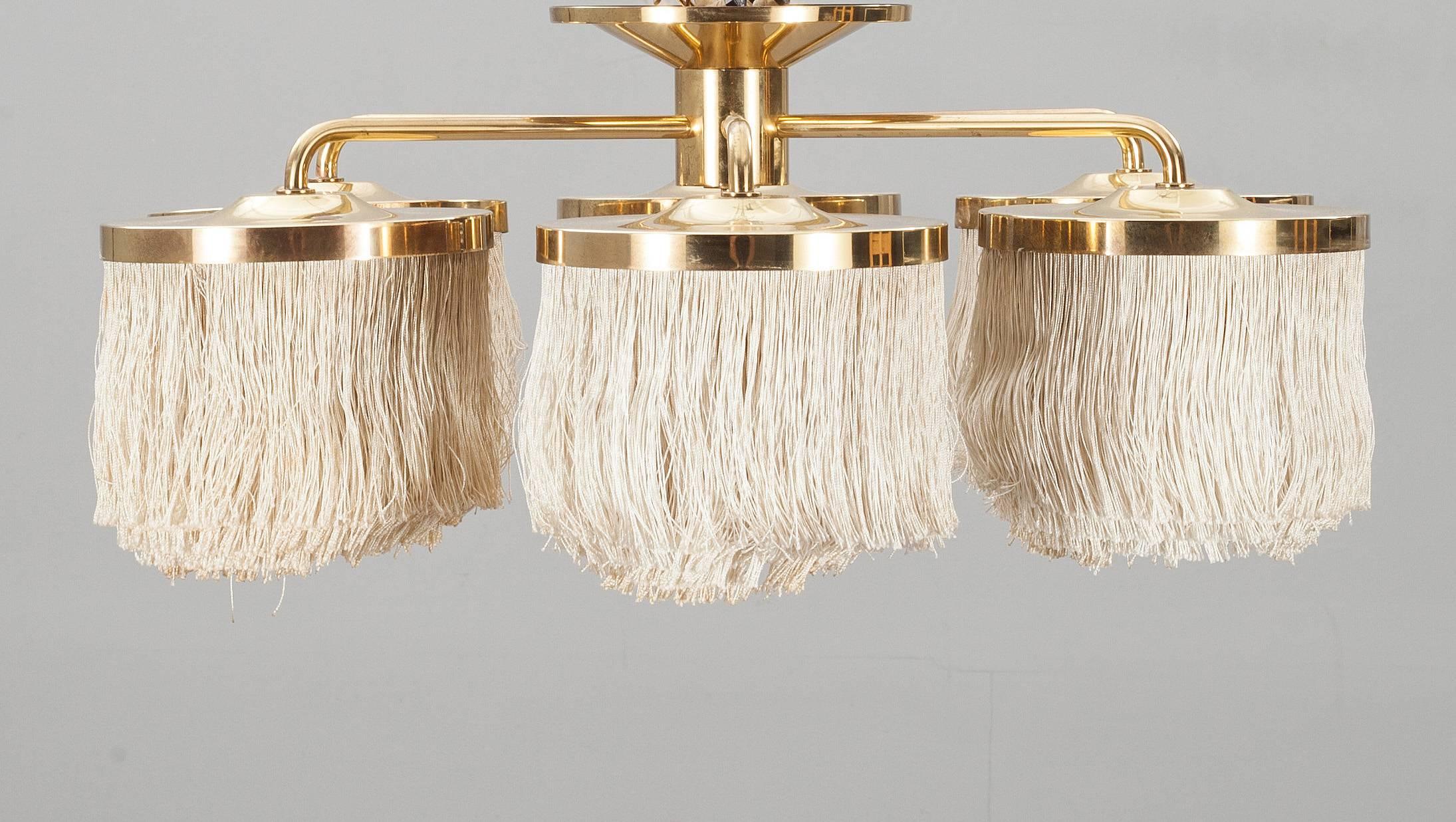 A chandelier with creme colored fringes and brass by Hans Agne Jakobsson. Made in Sweden by Markaryd, Sweden, end 1960s.