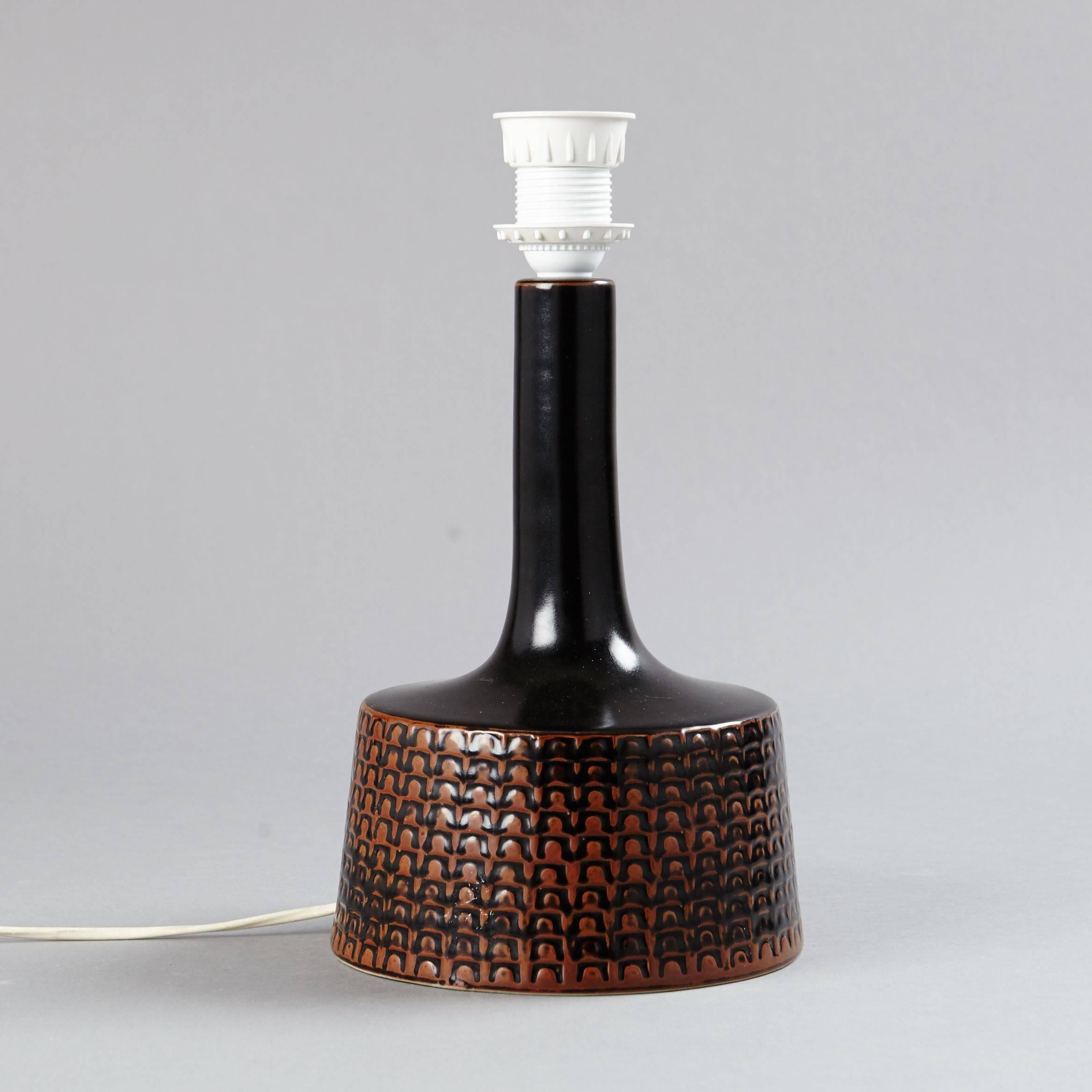 A handmade glazed dark brown and ochre red ceramic lamp by Stig Lindberg with an applied pattern relief. Signed 