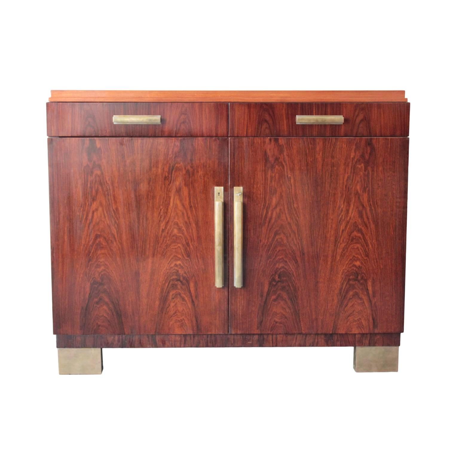 Distinctive server in rosewood having a (later) Carrara marble top, pair of drawers and a pair of doors enclosing a single adjustable shelf. Fitted with long brass handles. Beautiful original key. Raised on four brass lined block legs, aesthetically