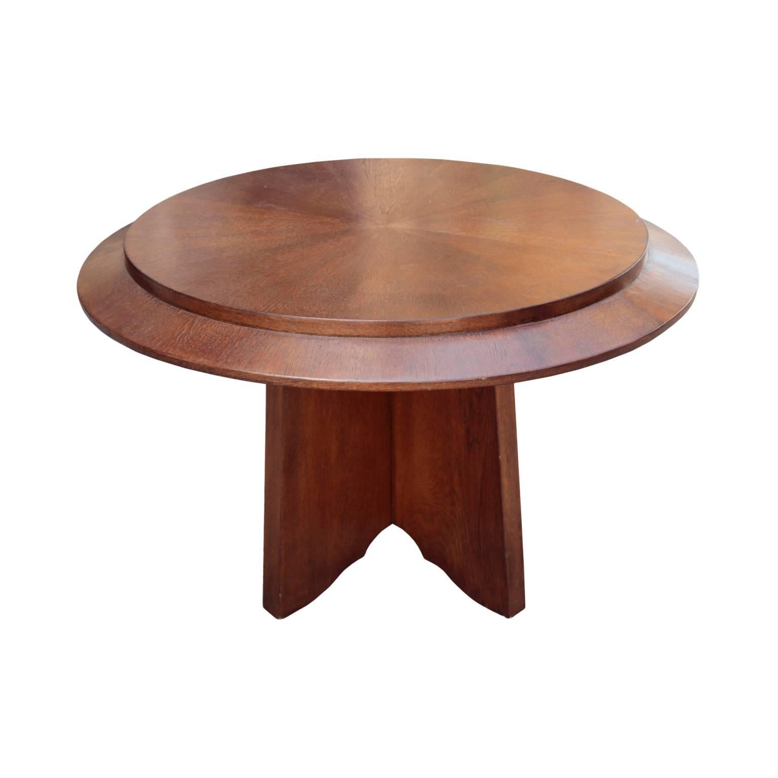 Well-designed table having a disc shaped dual layer top with protruding round central segment resting on the base of four corresponding shaped panels. In solid oak and oak veneer with sunburst bookmatched top, late 1930's-early 1940's.

