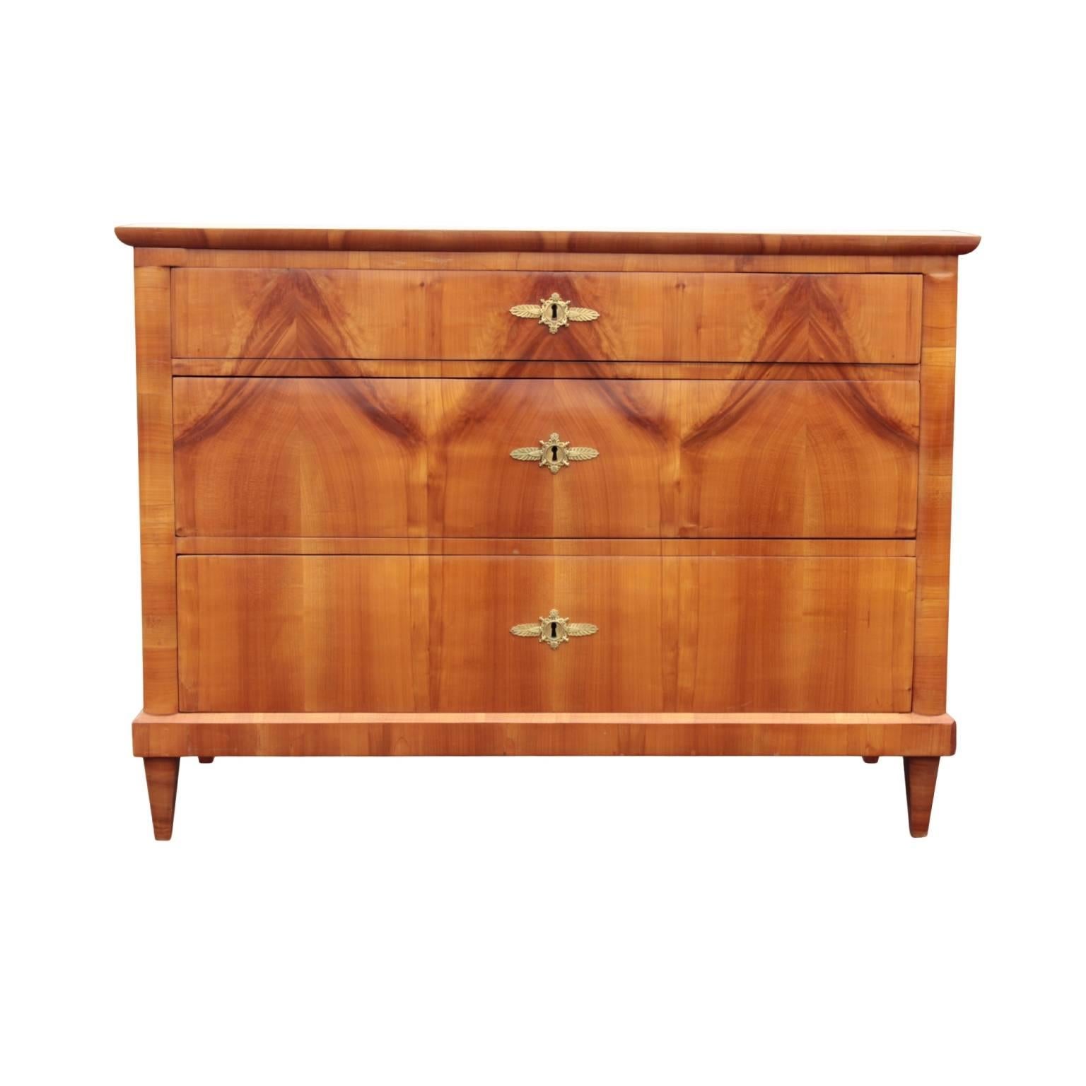 South German chest having subtly molded top and front edges; corpus with three drawers, top drawer of smaller height, in beautifully book-matched cherry with wood grain forming abstract swags. Drawers fitted with centrally positioned French