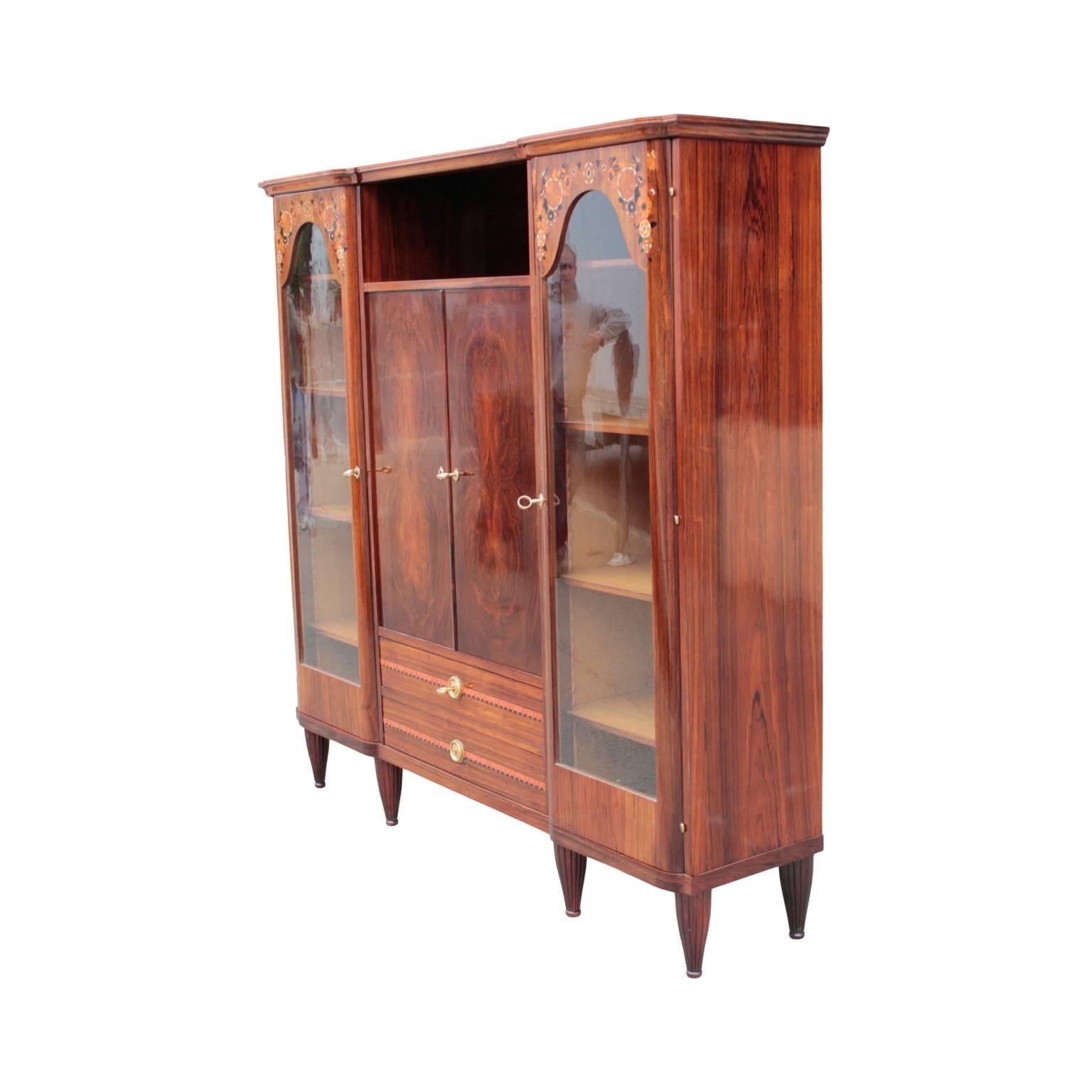 Superb French early Art Deco period vitrine/bookcase, most likely designed by Maurice Dufrene. Middle segment having an exposed display niche, pair of doors enclosing two shelves and a pair of drawers decorated with inlay in ebony, ivory and