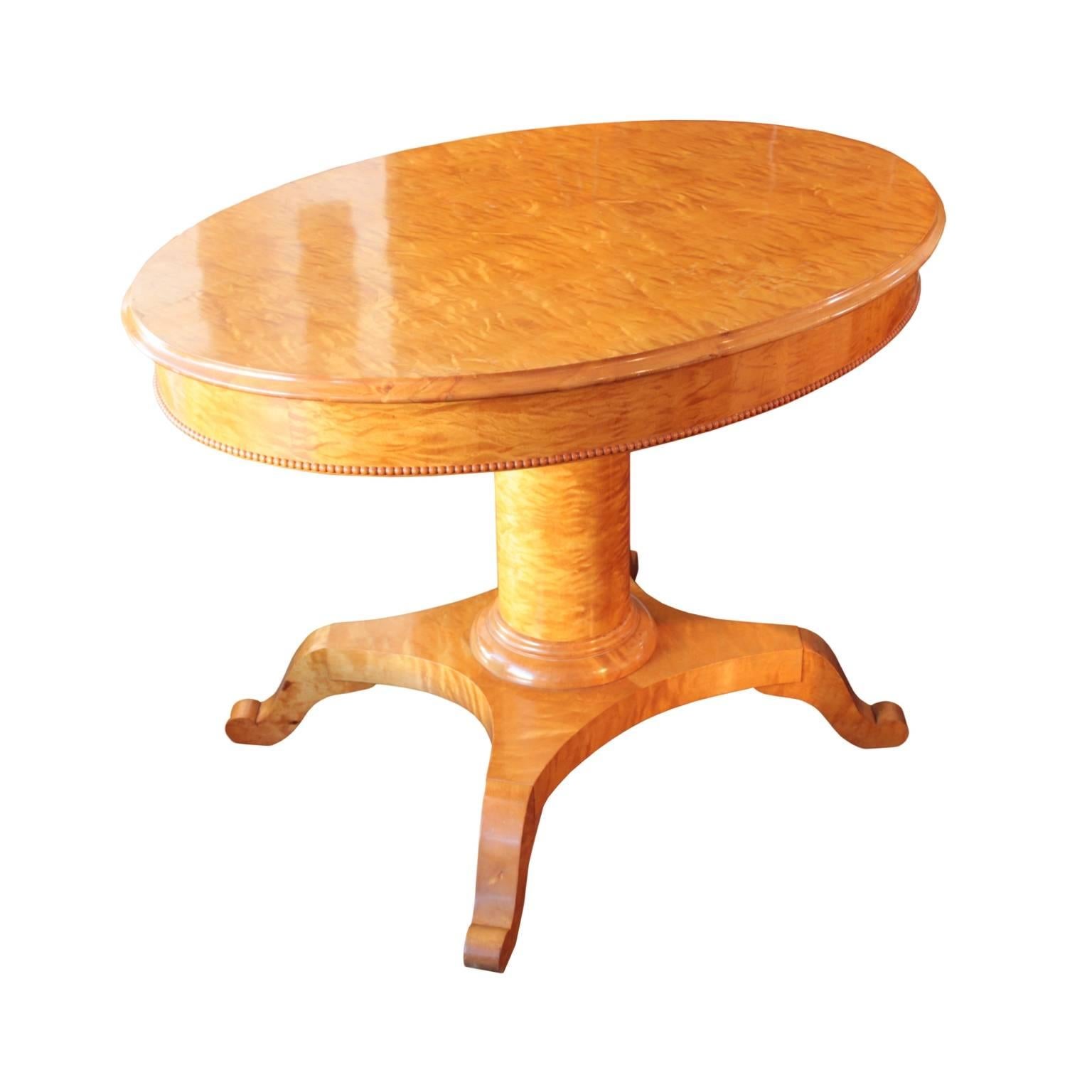 Table top with ogee edge and thick apron decorated with beaded lip molding on a column pedestal with double ring plinth, resting on a quadripartite base raised on four "S" scroll shaped legs. Rich flame birch veneer throughout. Karl Johan